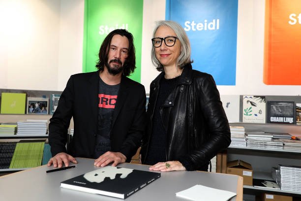 Keanu Reeves et l'artiste Alexandra Grant sont posés devant leur livre "Ode au bonheur" lors de "Paris Photo" au Grand Palais à Paris | Photo: Getty Images