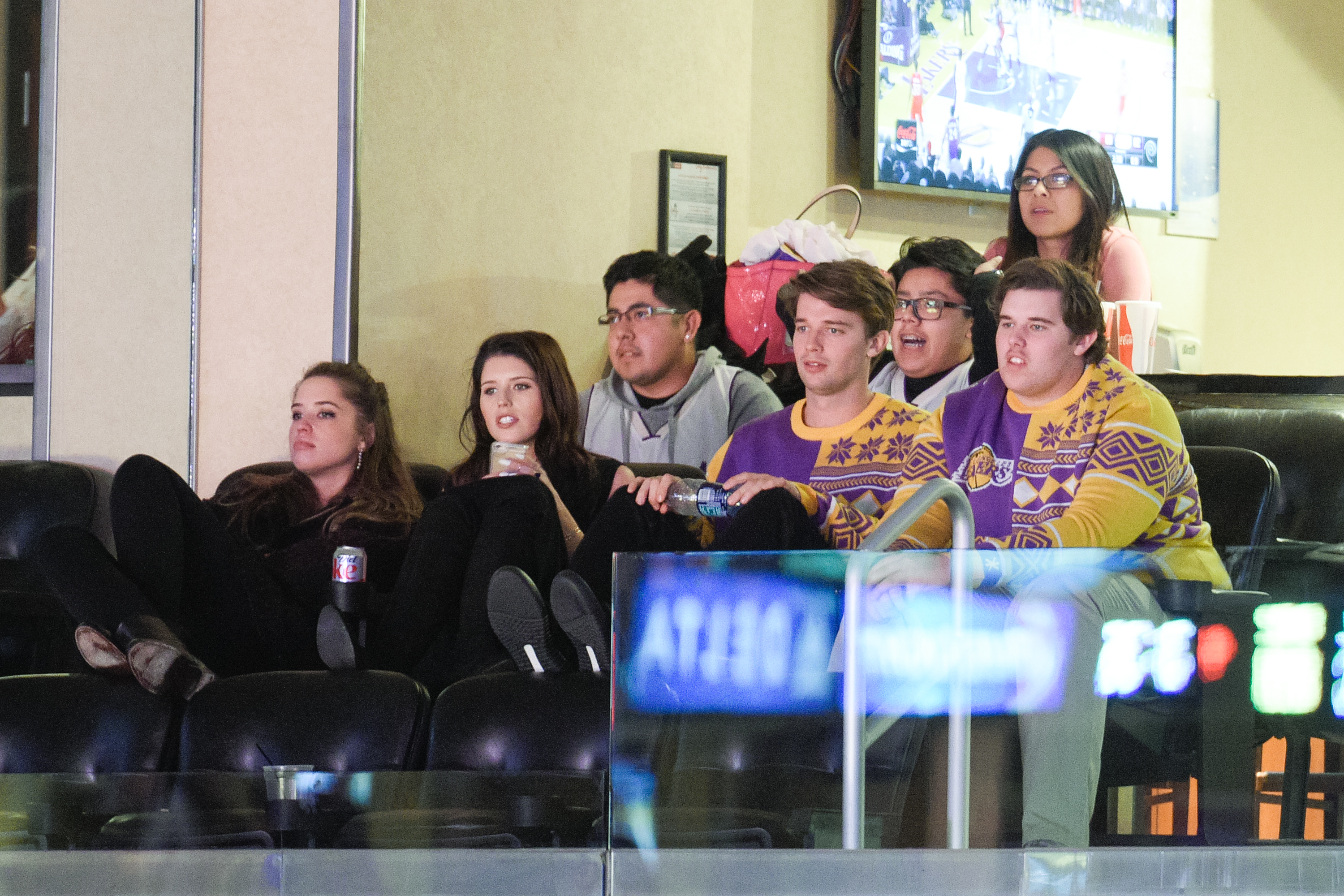 In another moment from the same game, Christopher sits beside his siblings, Christina, Katherine, and Patrick. Focused on the action, he blends in with the festive crowd, his holiday-themed sweater matching Patrick's while he leans forward with visible energy and attention.