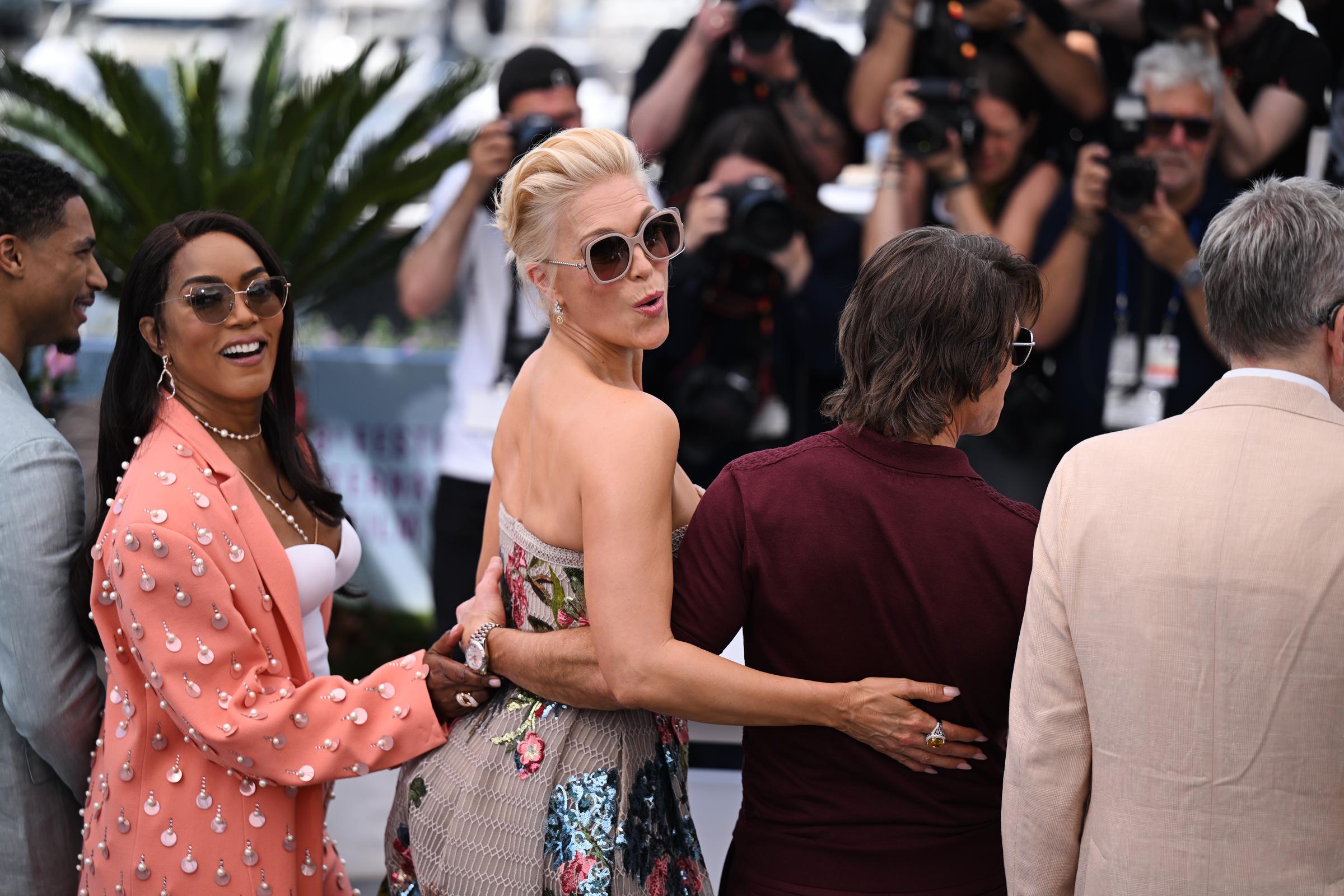 Hannah Waddingham strikes a playful pose as she, Tom Cruise, Angela Bassett, and other cast members arrive at the "Mission: Impossible – The Final Reckoning" photocall. Cruise, dressed in burgundy, stands center with his co-stars amid a flurry of camera flashes.