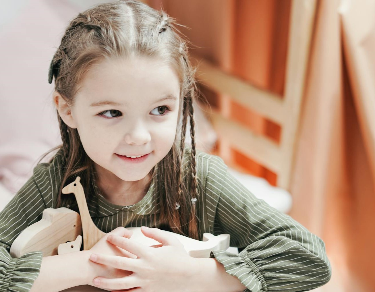 A little girl holding her toys and smiling | Source: Pexels