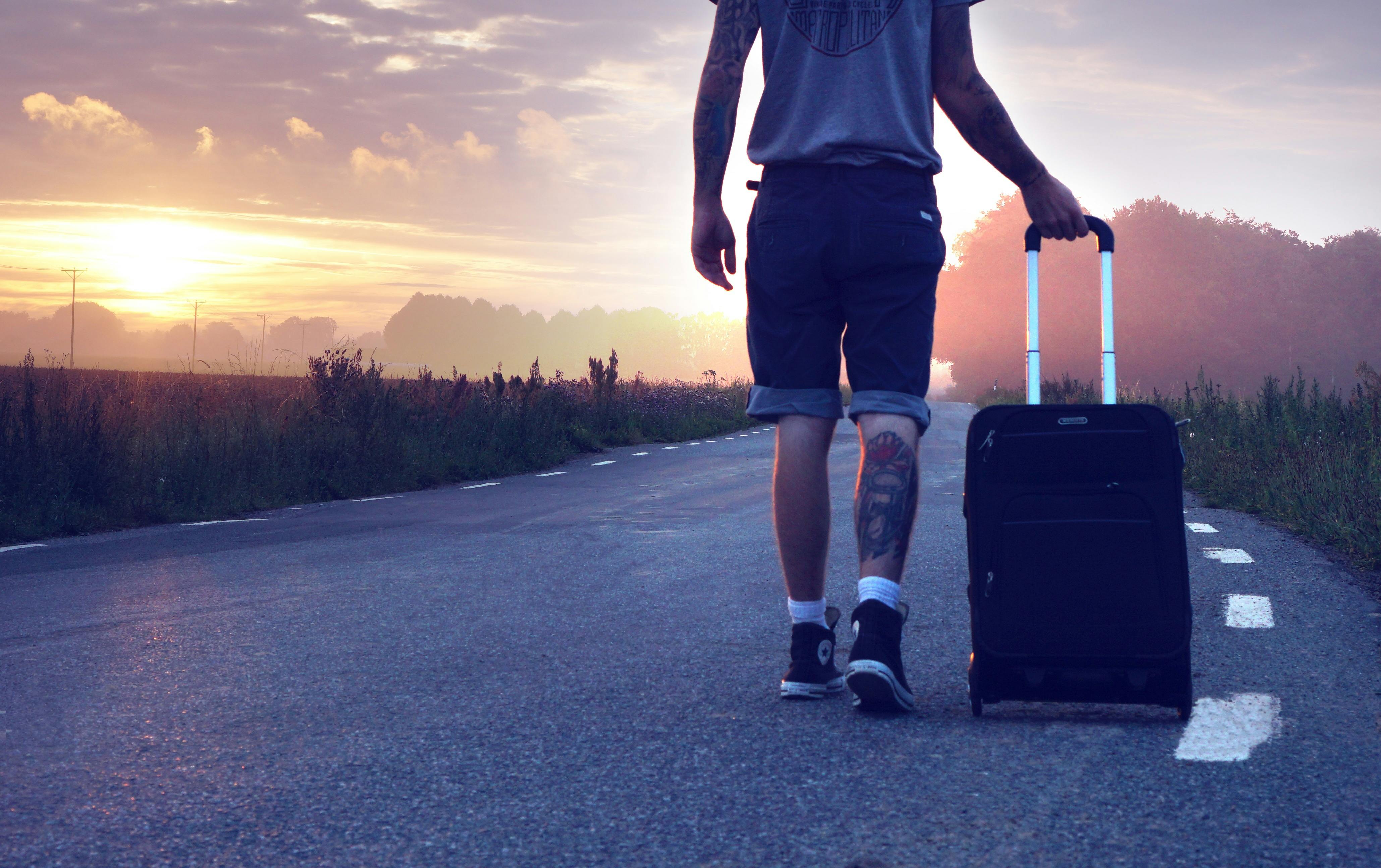 Man with luggage on road during sunset | Source: Pixabay