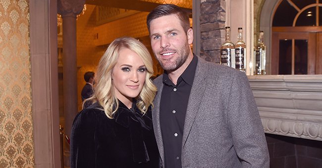 Carrie Underwood and Mike Fisher smile for a photo during an event. | Source: Getty Images