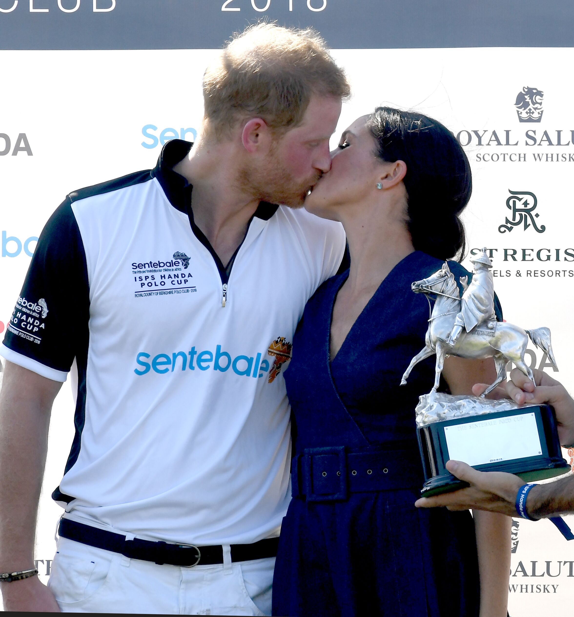Prince Harry and Duchess Meghan kiss as they pose with the trophy after the Sentebale ISPS Handa Polo on July 26, 2018, in Windsor, England | Photo: Anwar Hussein/WireImage/Getty Images
