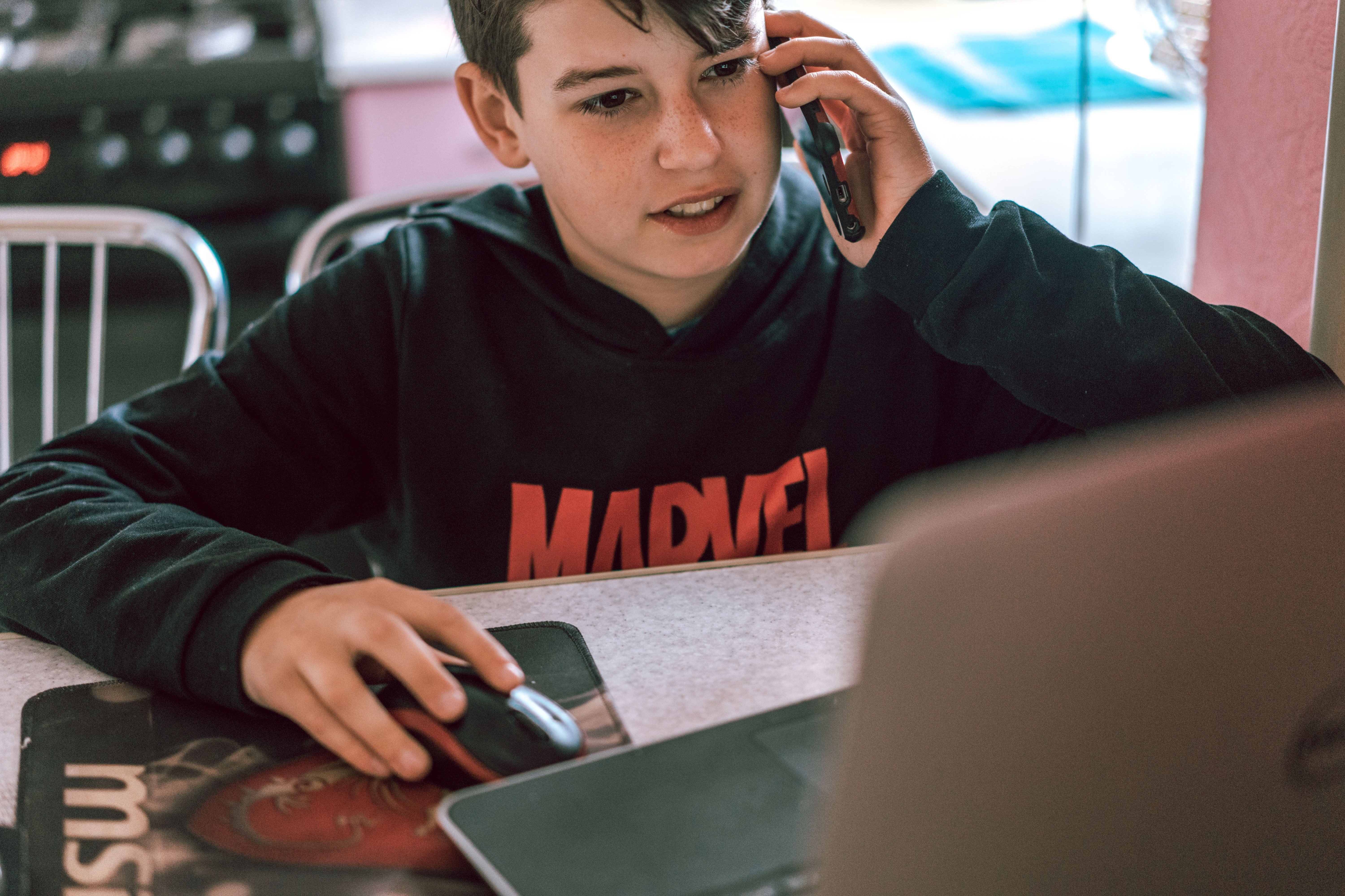 A boy placing a phone call while looking at a laptop screen | Source: Pexels