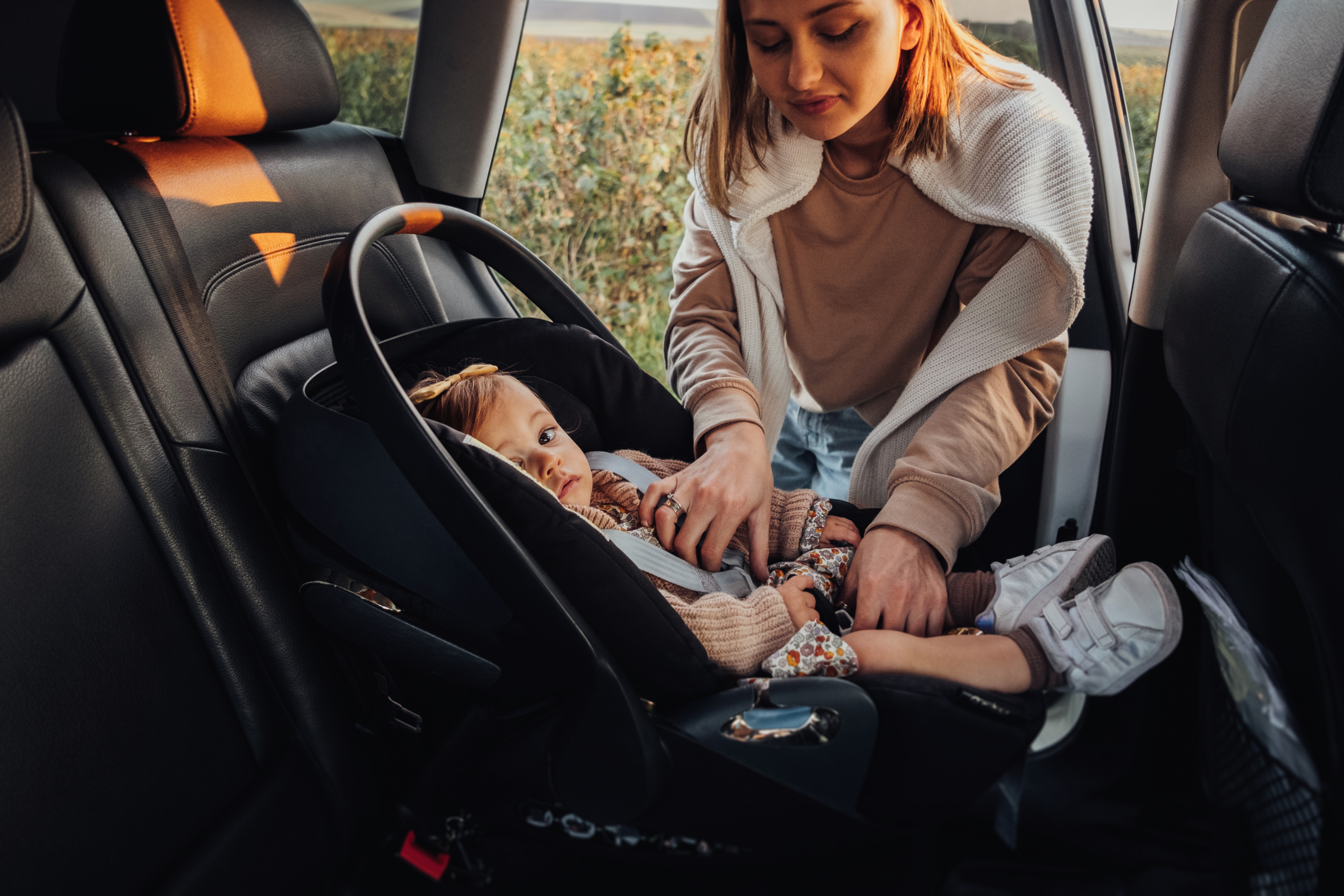 A young mother putting her baby girl in a car seat | Source: Shutterstock