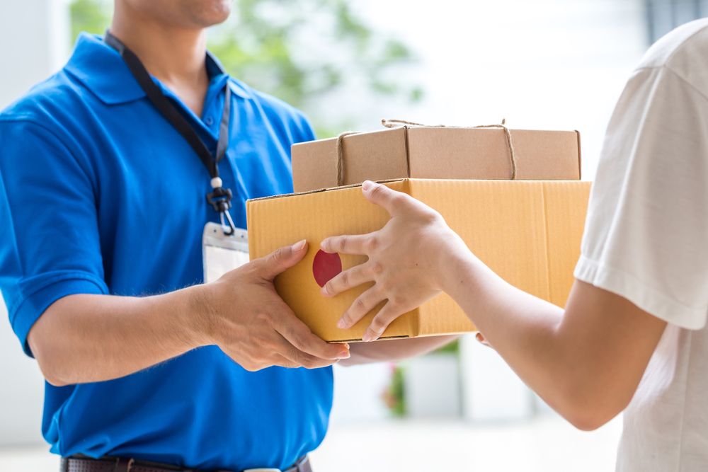 A deliveryman hands over packages to his customer. | Source: Shutterstock