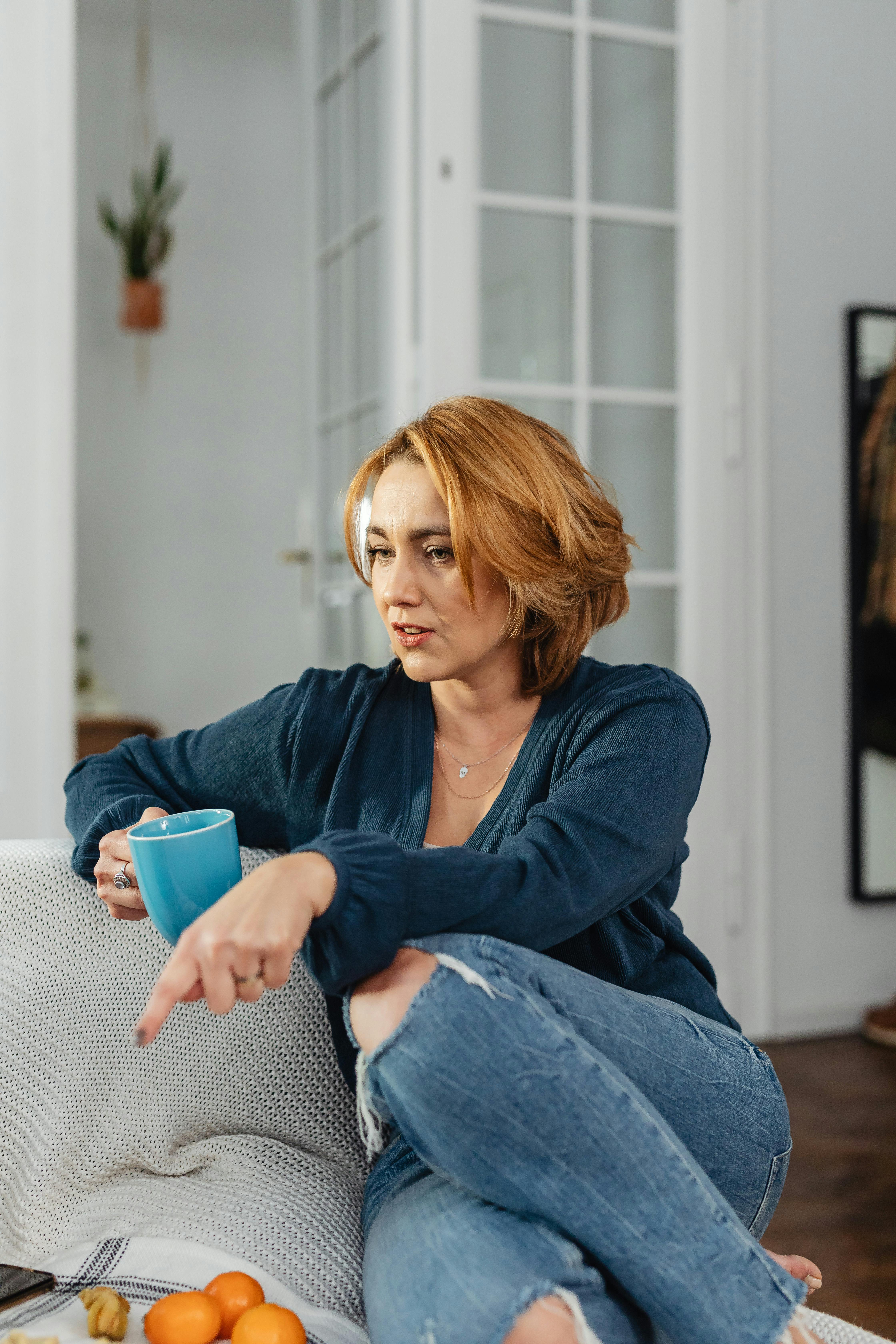 Woman sitting on the couch with a cup of coffee in hand | Source: Pexels