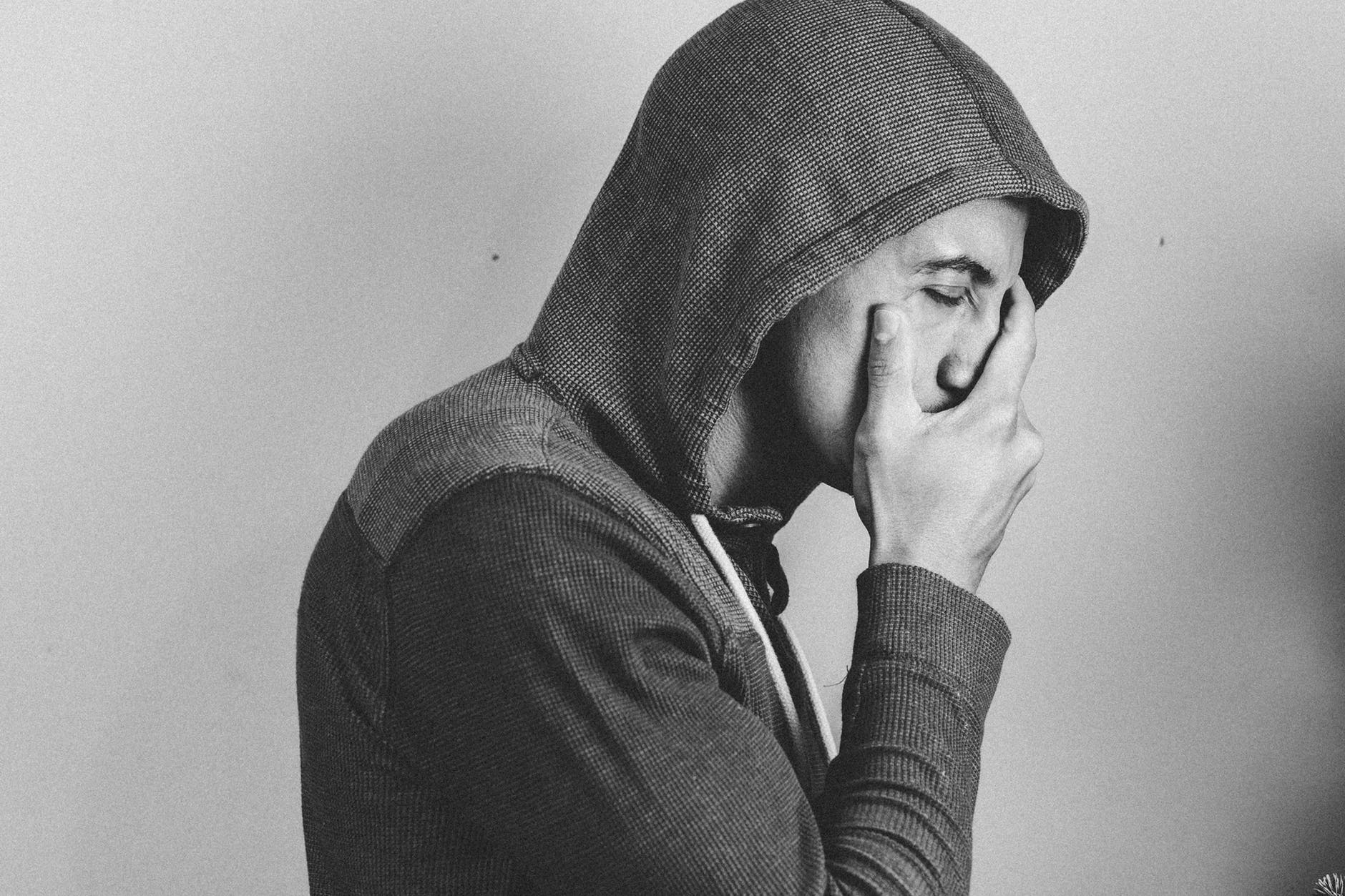 A black-and-white photo of a frustrated man covering his mouth. | Photo: Pexels