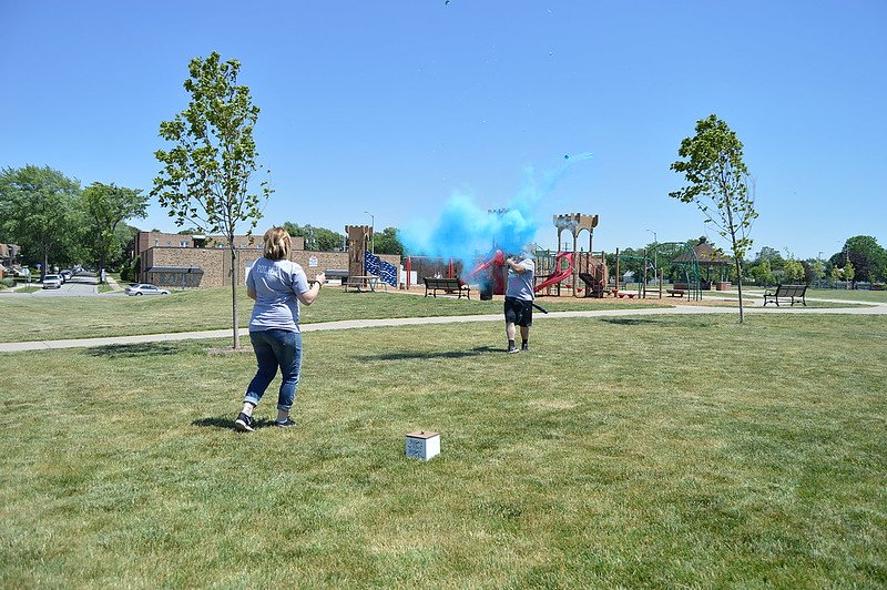 A couple blowing up color smoke crackers during a gender reveal. | Photo: Flickr