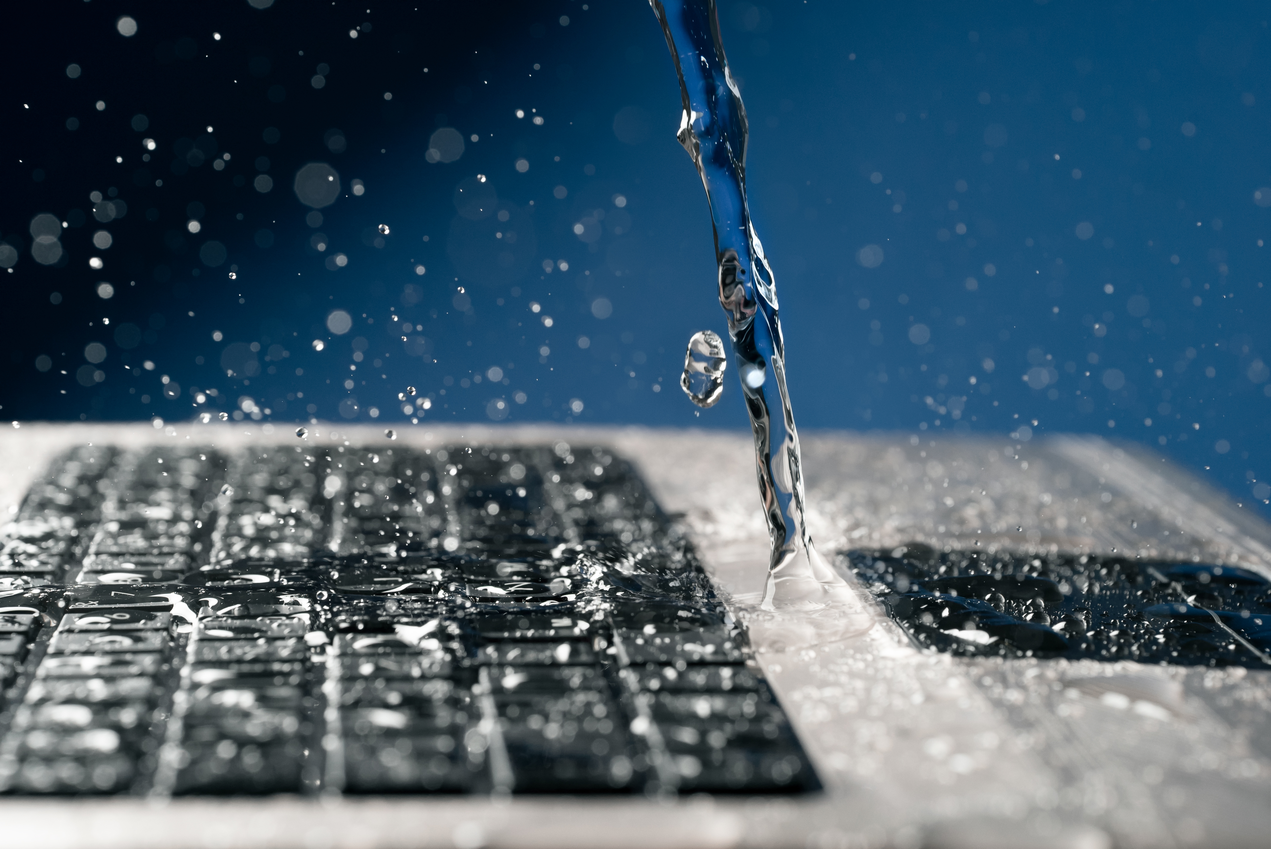 A stream of water pours on the laptop keyboard. | Source: Shutterstock