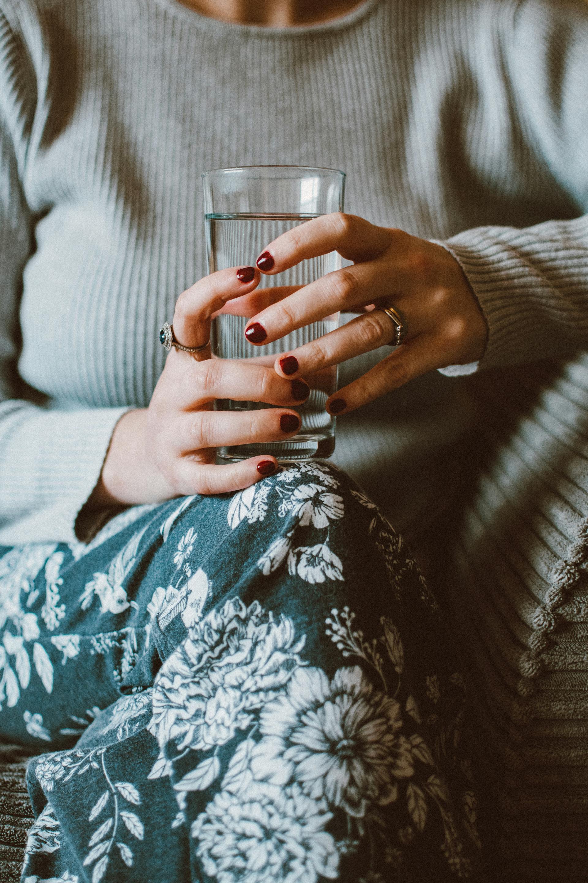 A woman sitting on a sofa while holding a glass of water | Source: Pexels