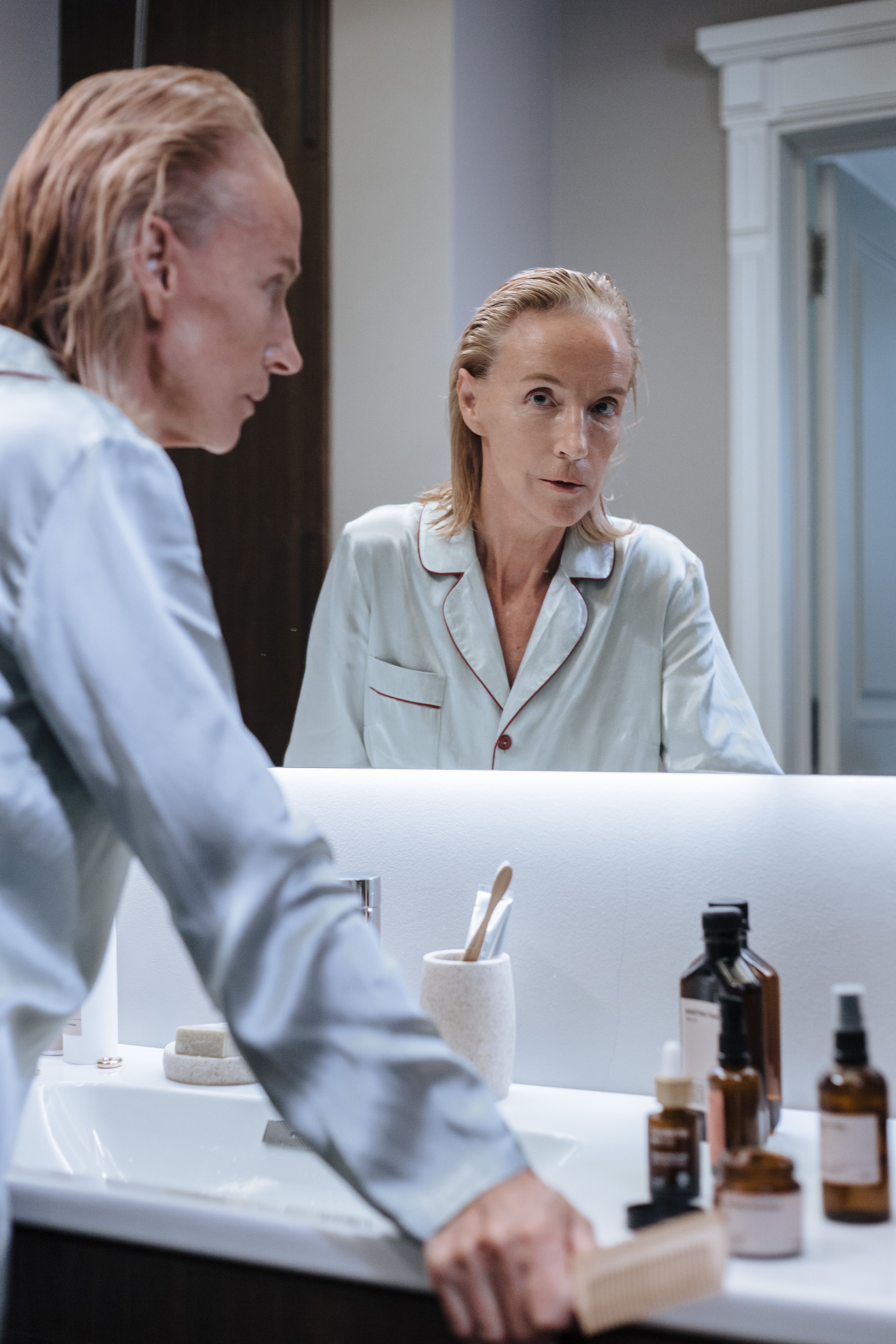 Woman observing herself through a bathroom mirror | Source: Pexels