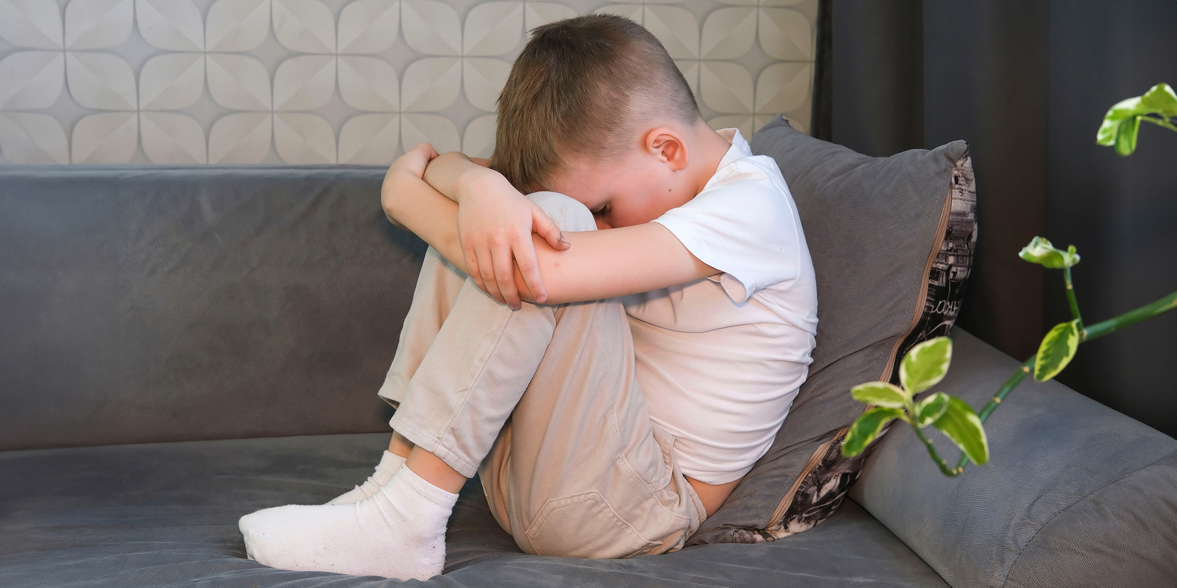 An upset little boy sitting on a couch | Source: Shutterstock