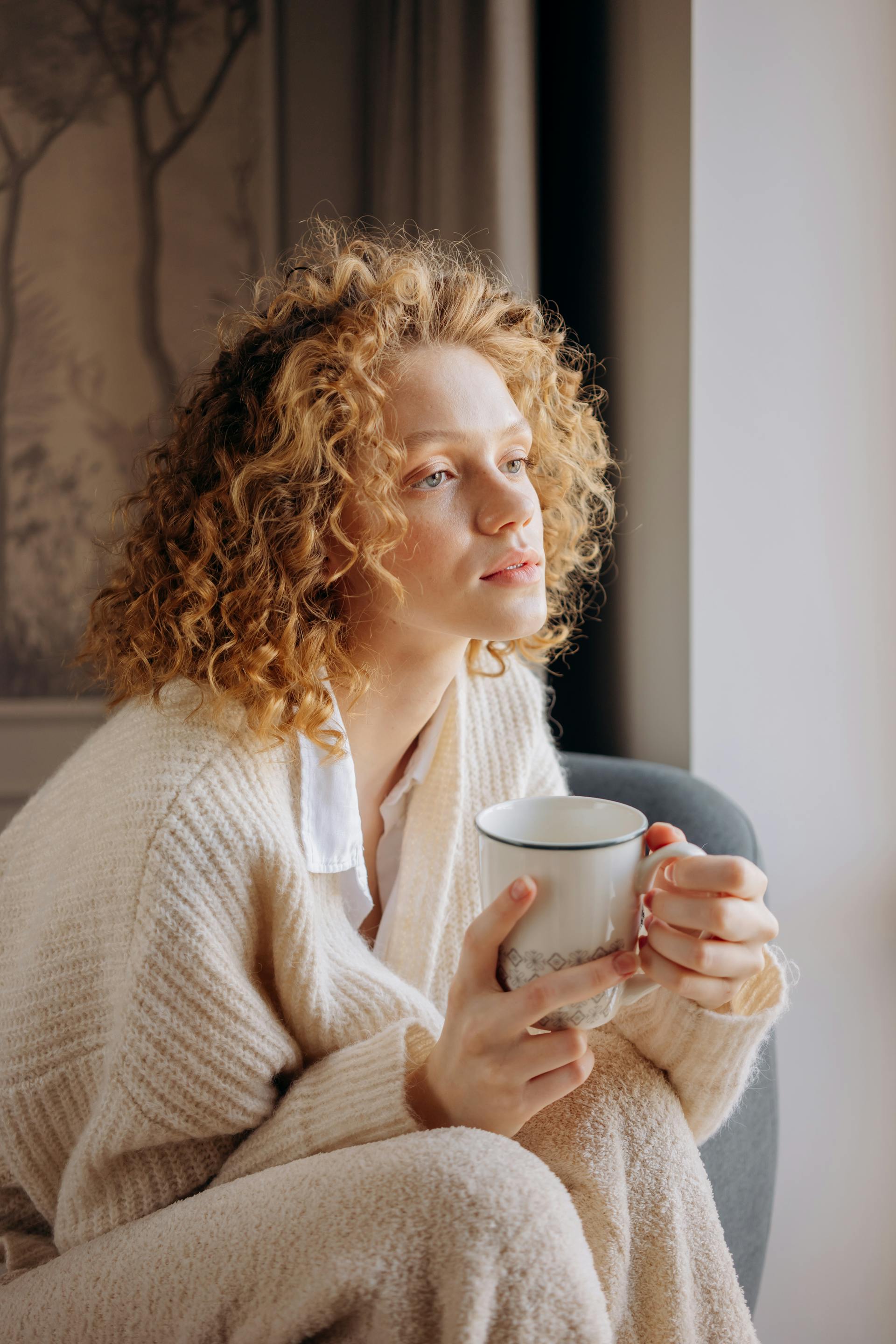A curly-haired woman holding a mug | Source: Pexels