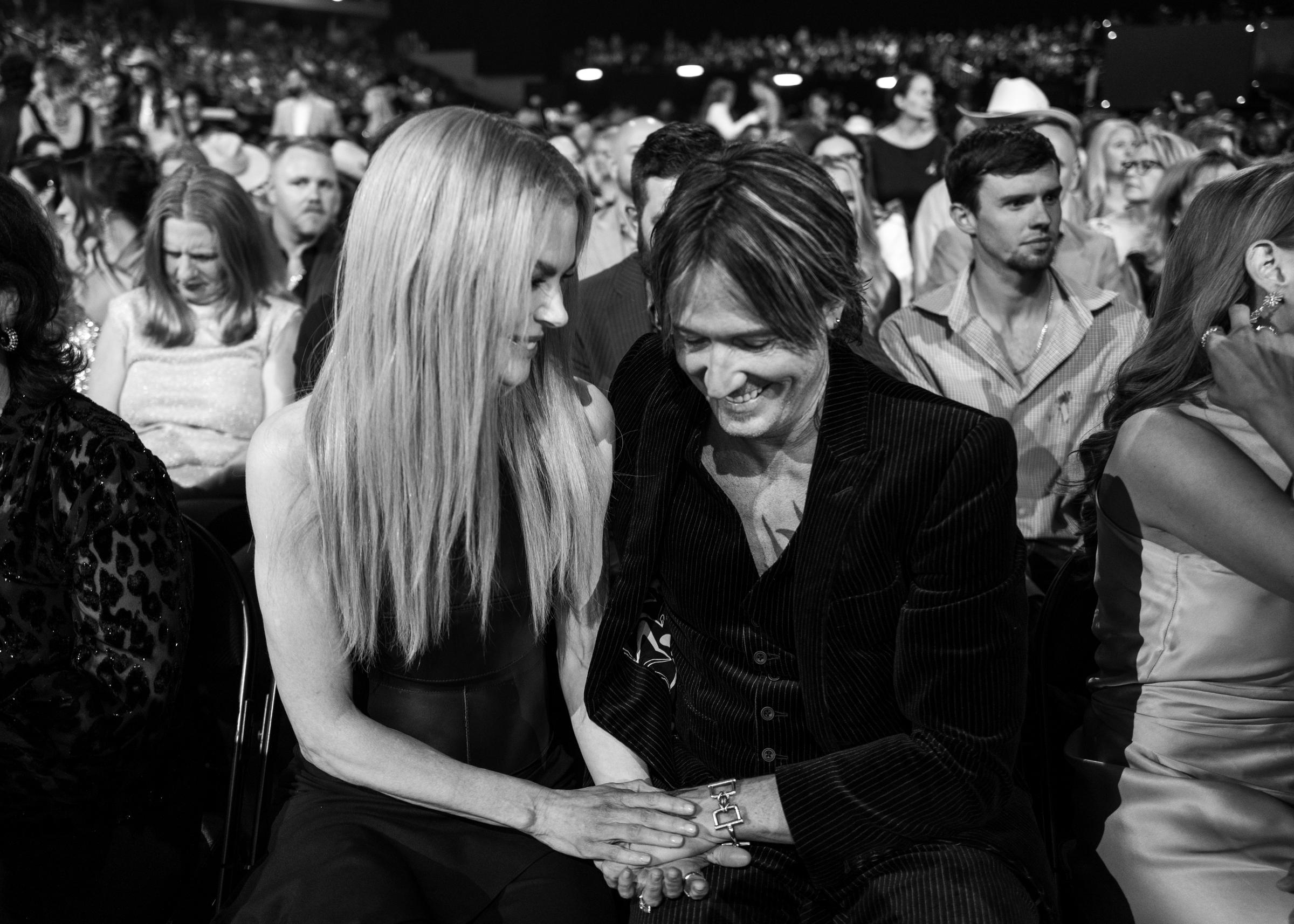 In a black-and-white shot full of texture and tenderness, Nicole Kidman and Keith Urban glance down at their interlocked hands. It’s an intimate freeze-frame amid the noise of a crowded room.