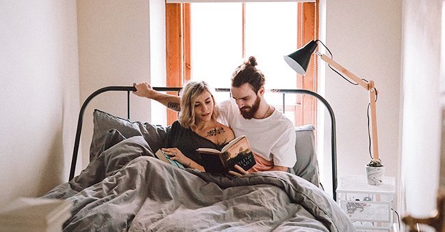 A happy couple reading together in their apartment | Photo: unsplash.com/Toa Heftiba