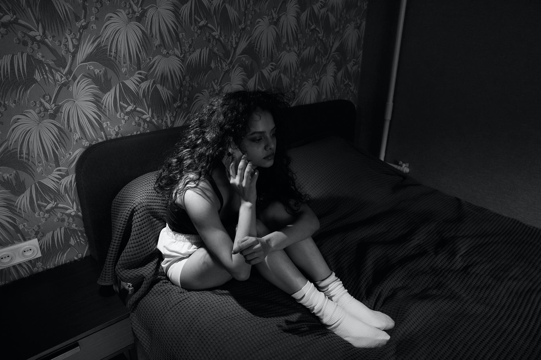 Joven sentada en una cama hablando a través del teléfono celular. | Foto: Pexels