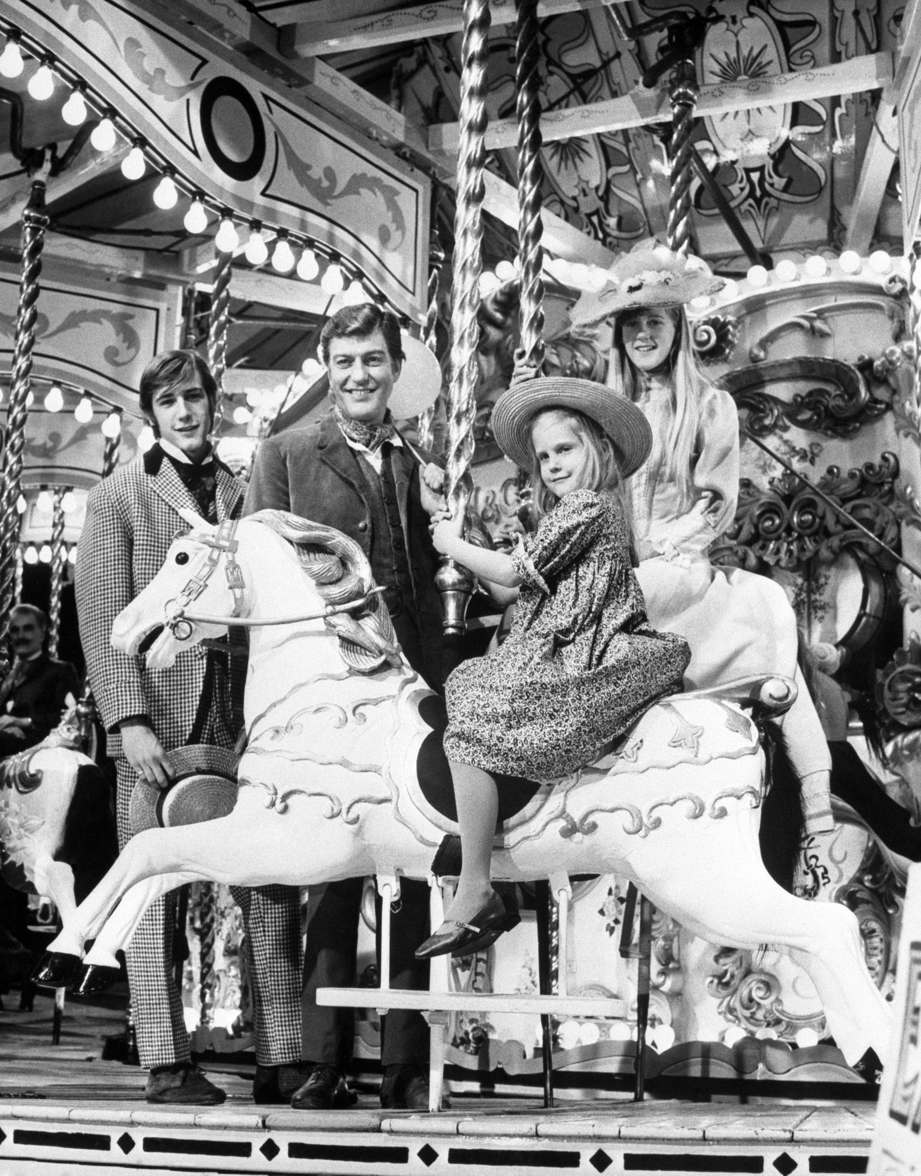 Six-year-old CARRIE BETH and her sister STACEY, 13, steal the scene here from their brother BARRY, 16, and father DICK VAN DYKE, who watch as the girls go round the merry-go-round at Pinewood Studios. in 1968. | Source: Getty Images