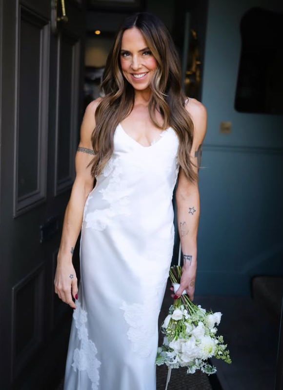 A closer portrait revealed the delicate floral embroidery woven into the satin gown, details that were less visible in the first wedding photos. She paired the dress with loose waves and a simple white wildflower bouquet, keeping the focus on the minimalist look. | Source: Instagram/timmsy