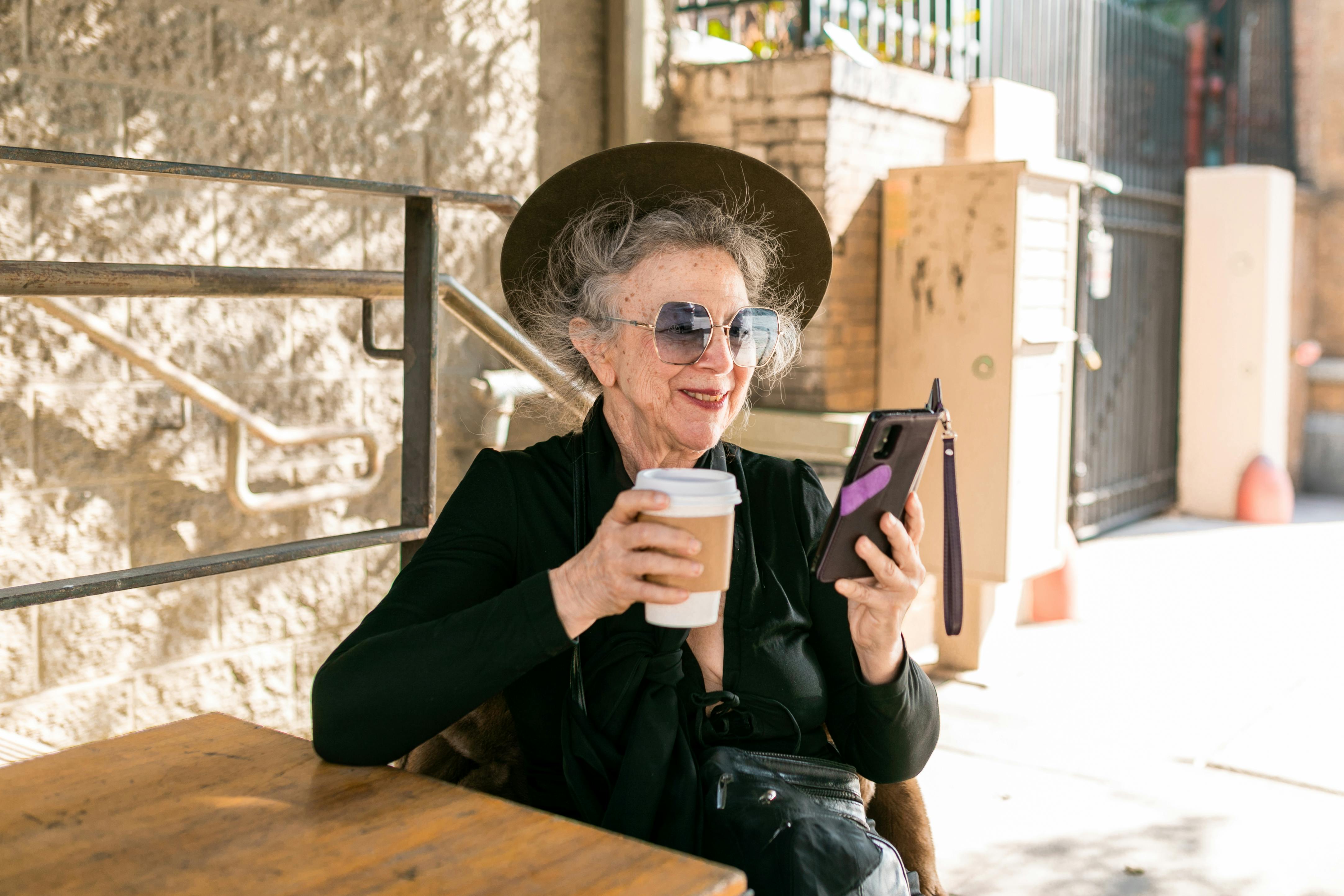 Woman drinking coffee while using her smartphone | Source: Pexels