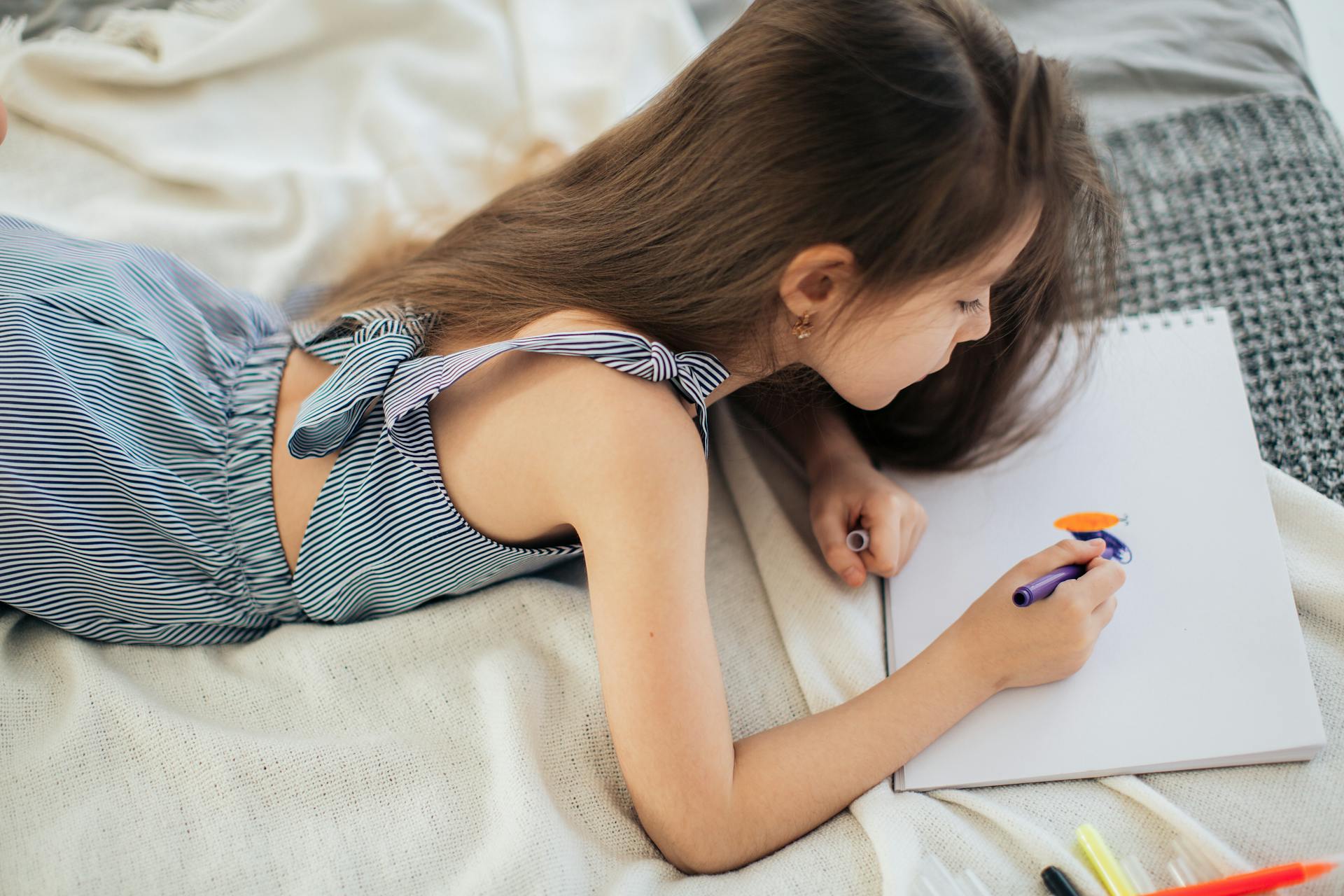 A girl coloring on her bed | Source: Pexels