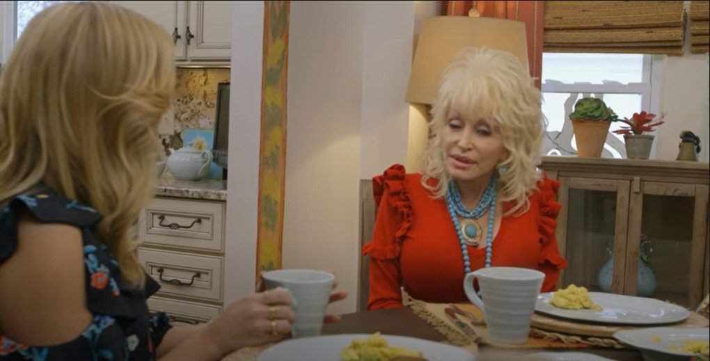 Dolly Parton and Reese Witherspoon discussing at Dolly Patron’s kitchen | Source: YouTube/Reese Witherspoon x Hello Sunshine is the name