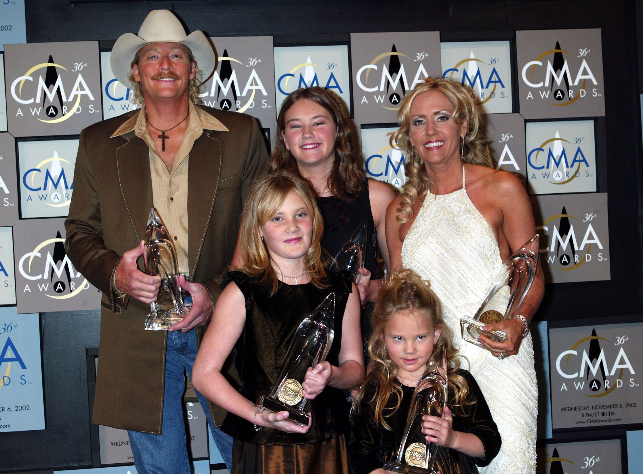Alan Jackson poses with his 5 awards with a little help from his family - wife Denise, and Daughters Mattie - 12, Ali - 9, and Dani - 5, at the 36th annual Country Music Association Awards at the Grand Ole Opry House in Nashville, Tennessee, November 6, 2002. | Source: Getty Images