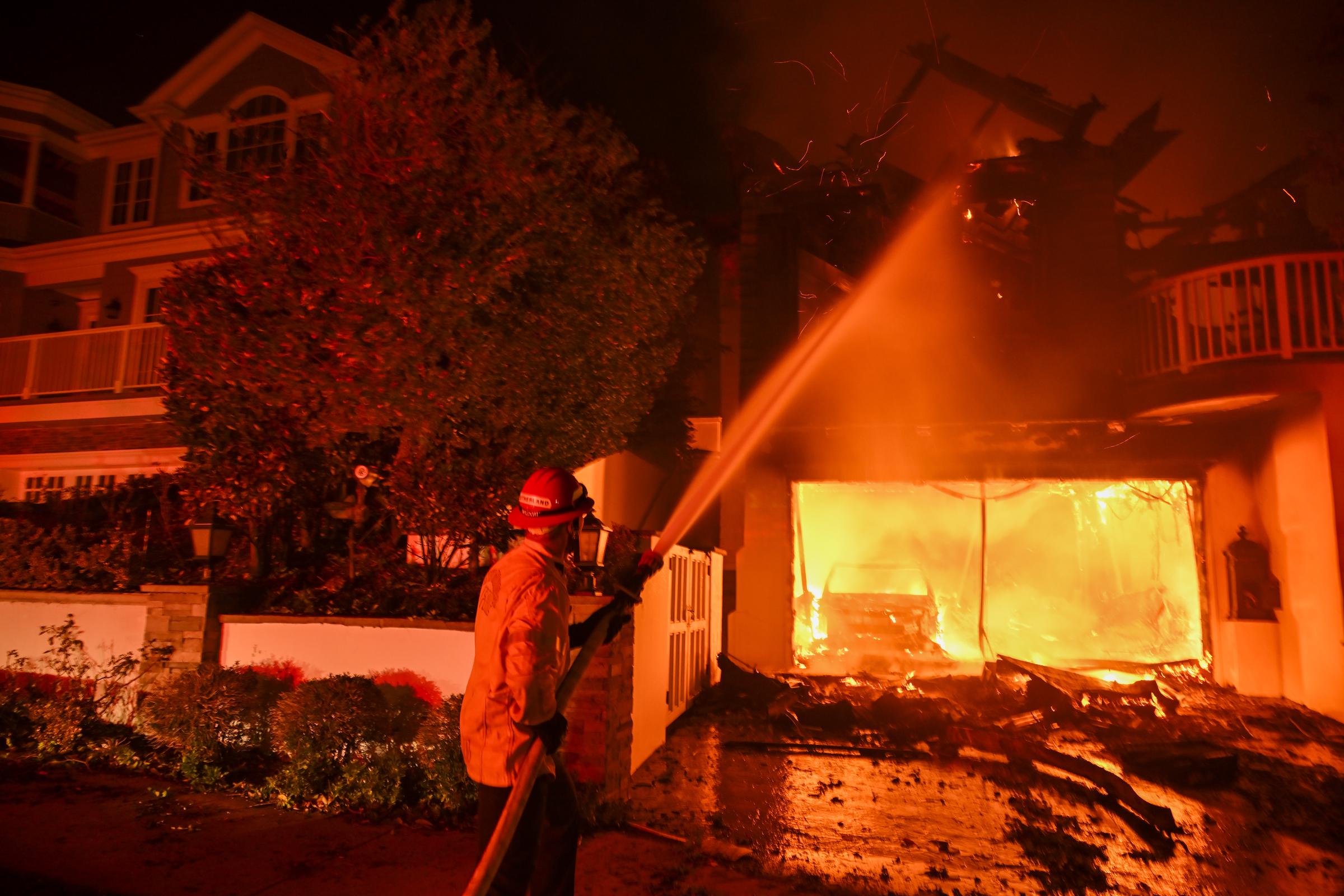 A firefighter dousing a home caught on fire in Pacific Palisades, California on January 8, 2025. | Source: Getty Images