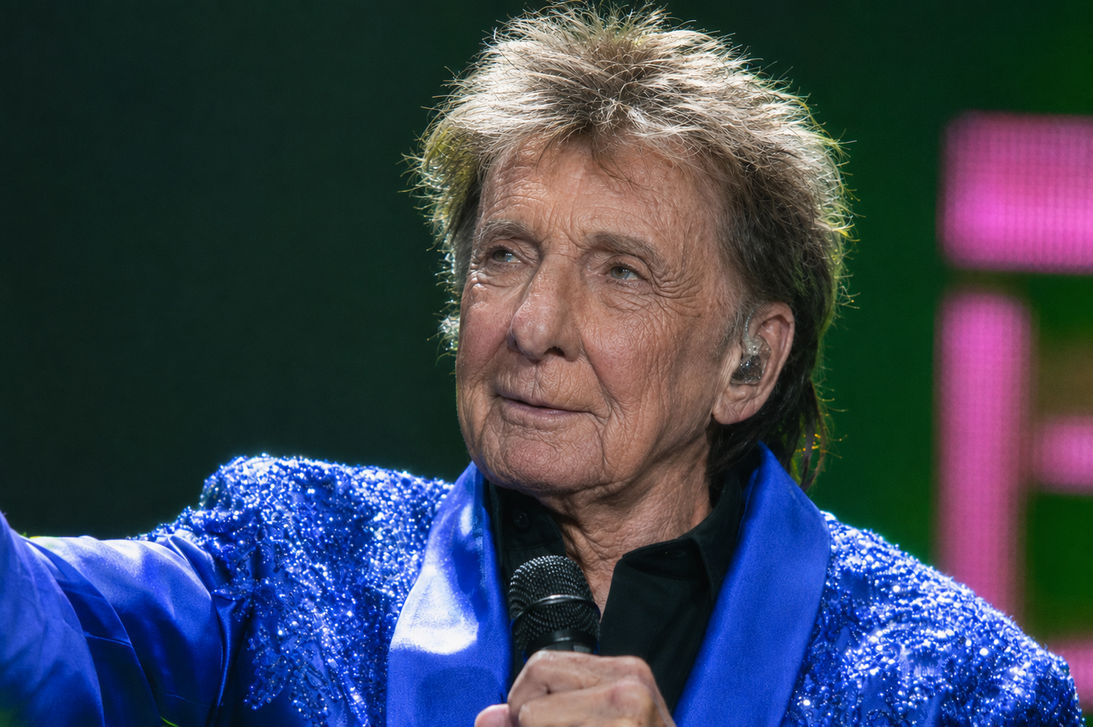 The bright blue jacket keeps the image tied to Manilow's polished stage persona. Against that familiar look, the older face creates a stronger contrast and makes the rendering feel like an alternate version of the same performer. | Source: ChatGPT