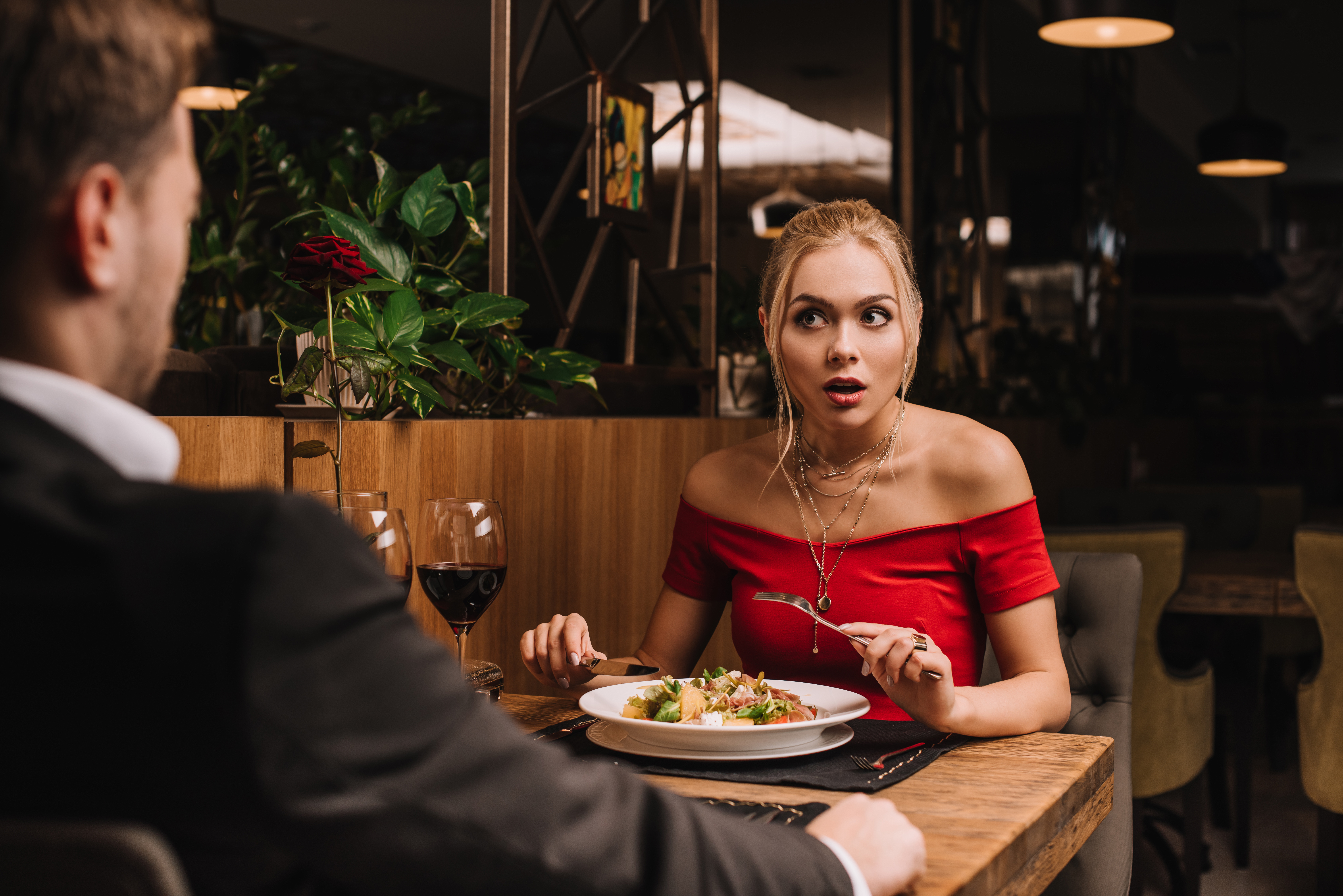 A young woman looks at the man in shock during dinner | Source: Shutterstock