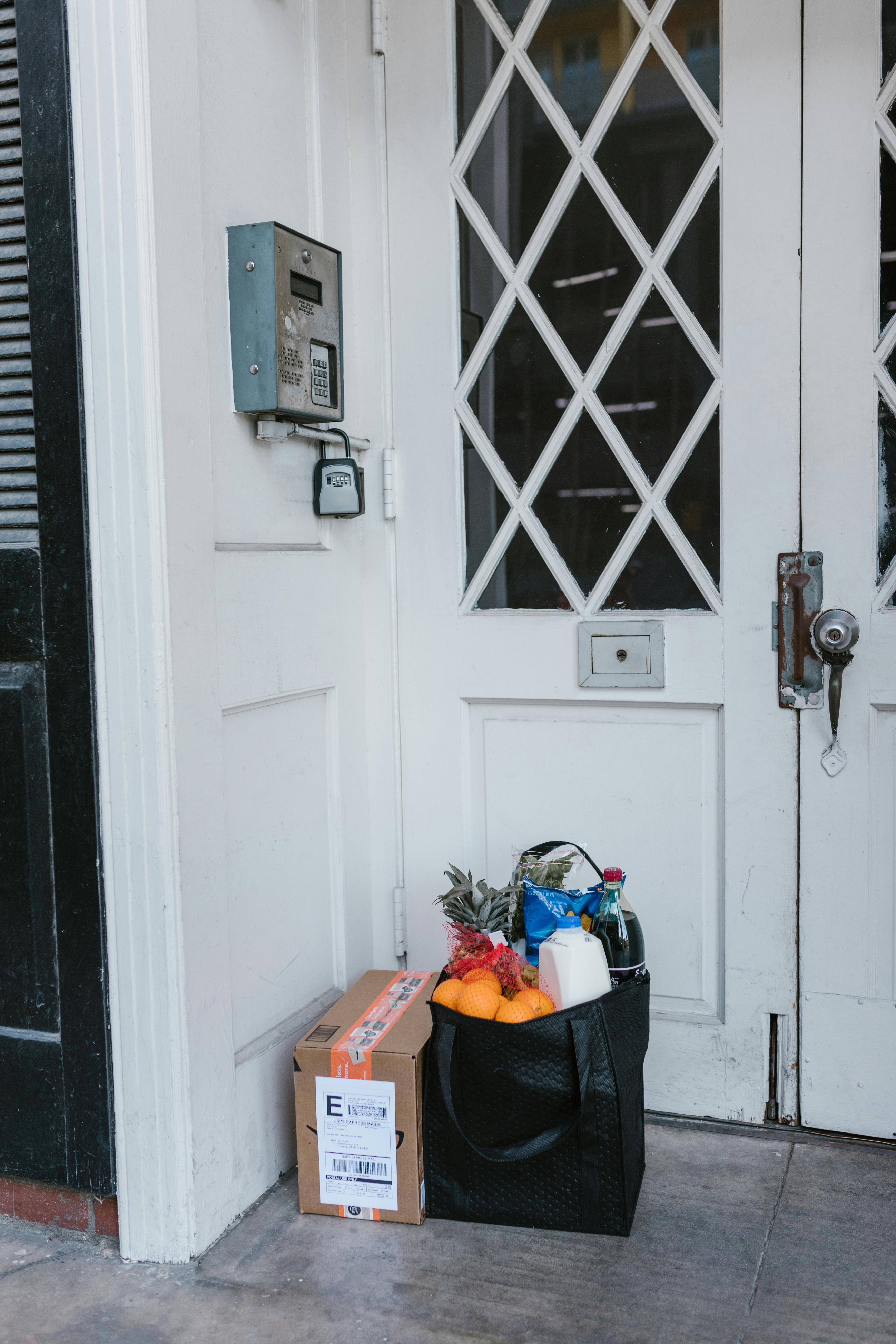 Grocery bag and a parcel on a doorstep | Source: Pexels