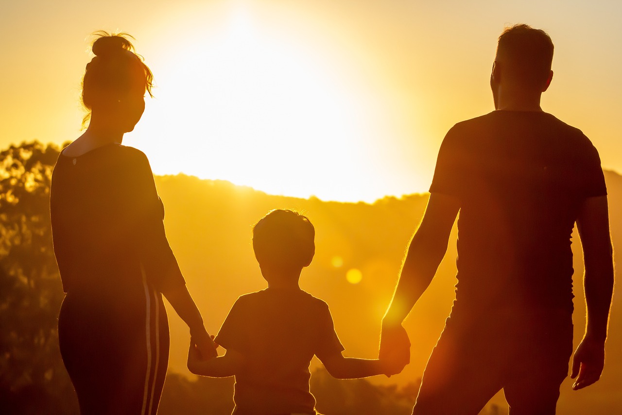 A couple with their child staring out at the sunset | Source: Pixabay