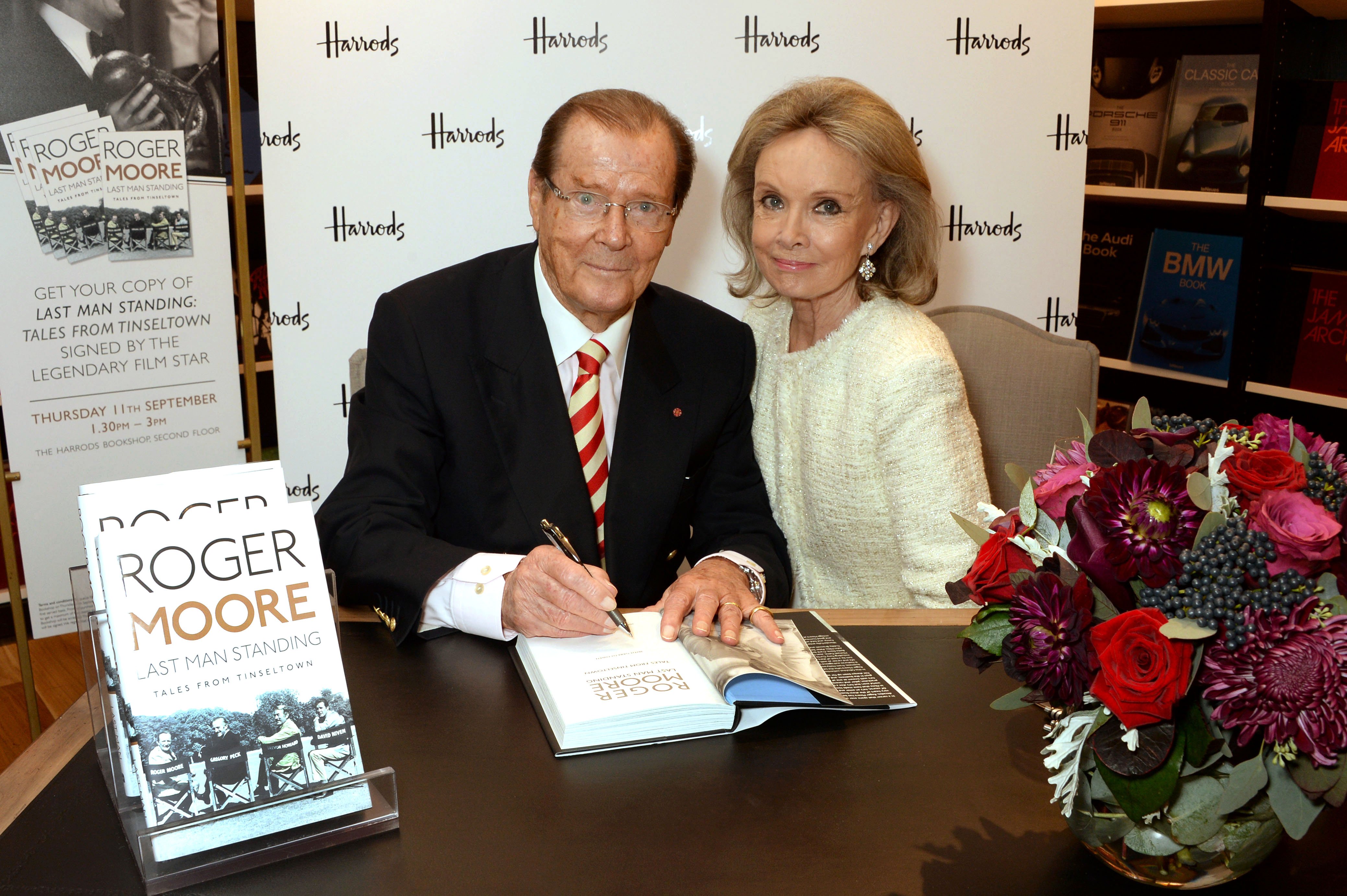 Roger Moore signs copies of his new book "Last Man Standing: Tales from Tinseltown" alongside wife Kristina Tholstrup at Harrods Bookshop on September 11, 2014 in London, England | Source: Getty Images