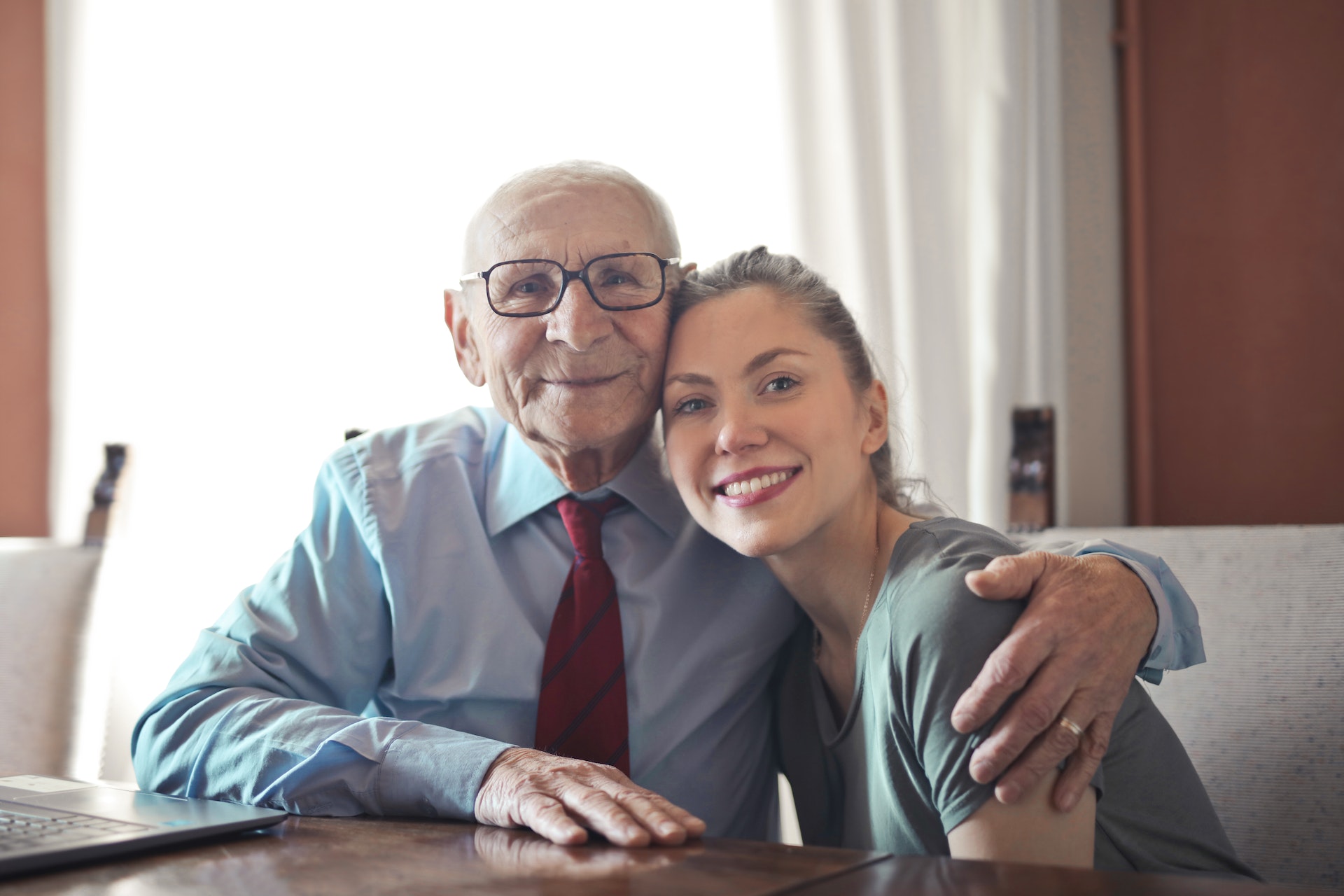 A young girl smiles while embracing her elderly grandfather | Source: Pexels