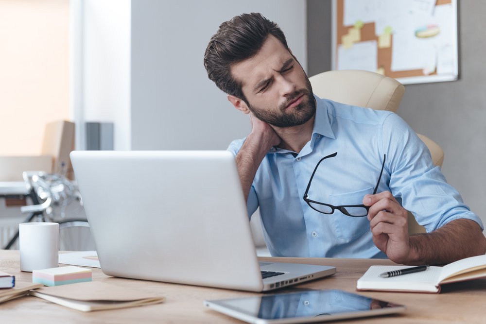 Hombre en oficina con dolor de cuello. Fuente: Shutterstock Hombre en oficina con dolor de cuello. Fuente: Shutterstock