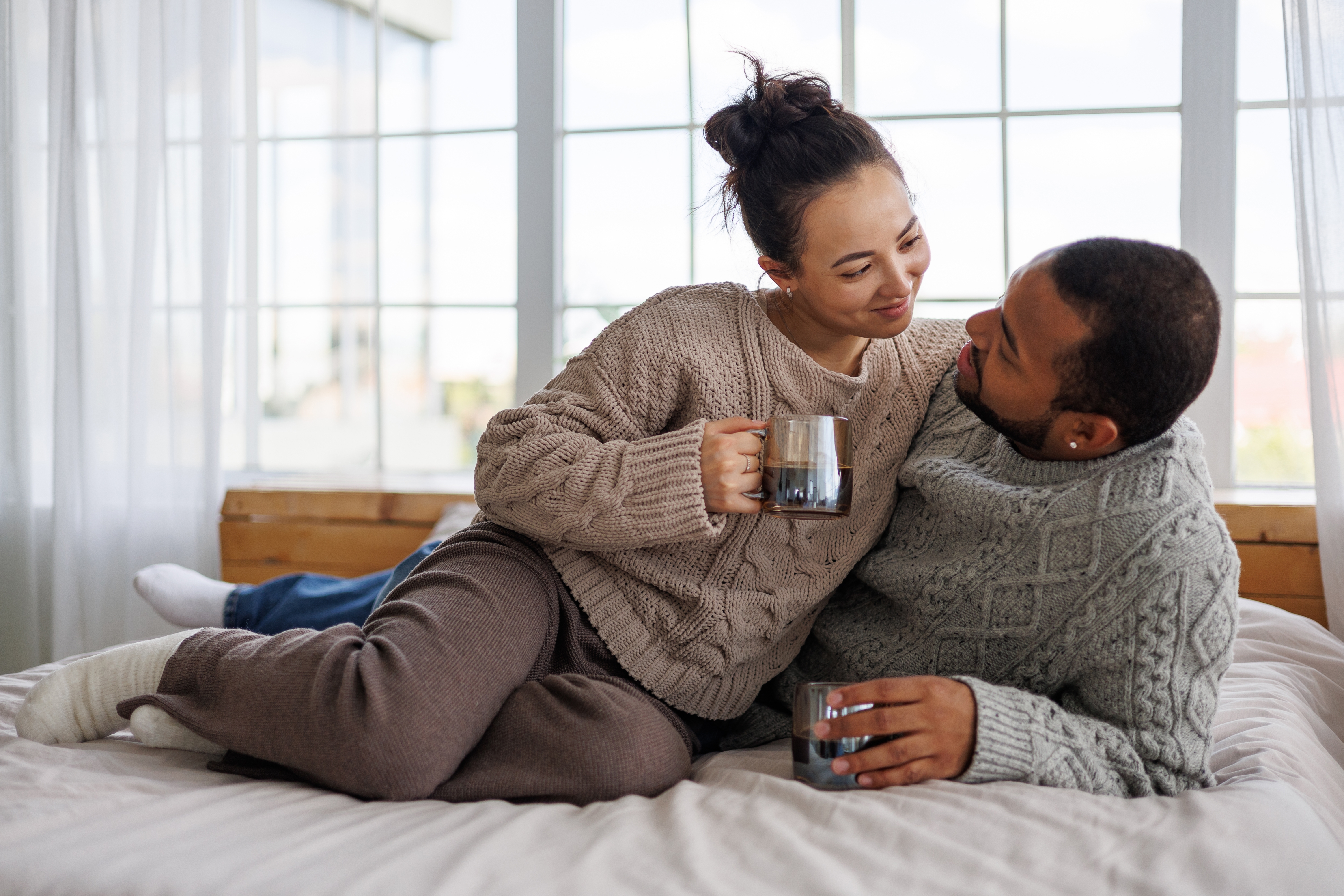 A happy couple looking cozy on a bed | Source: Shutterstock
