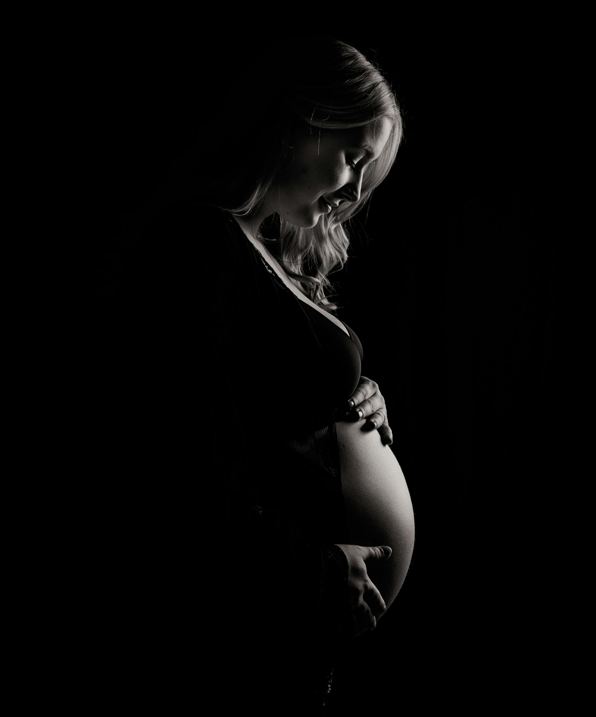 A grayscale photo of a pregnant woman holding her baby bump | Source: Pexels