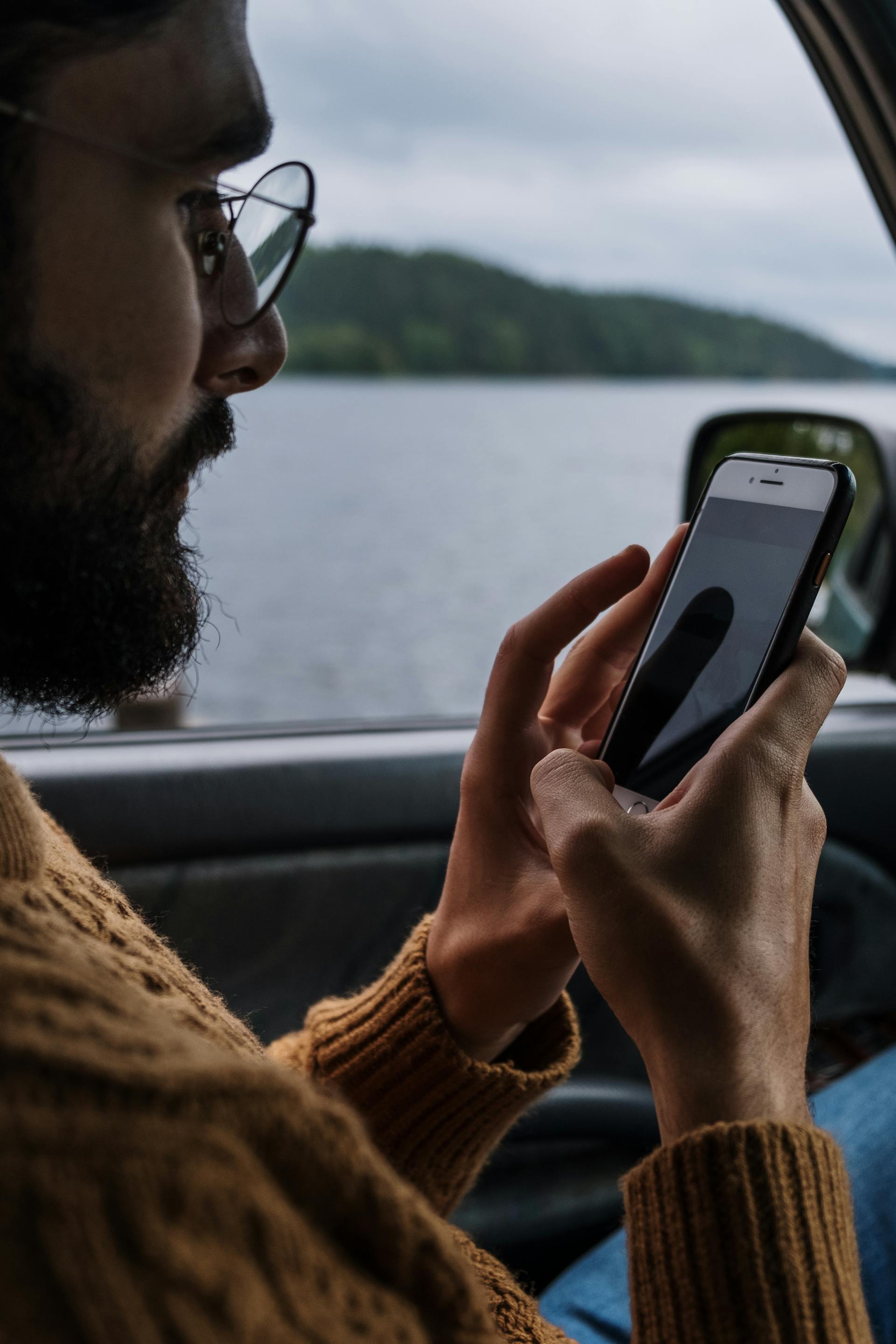A man inside a car texting on his phone | Source: Pexels