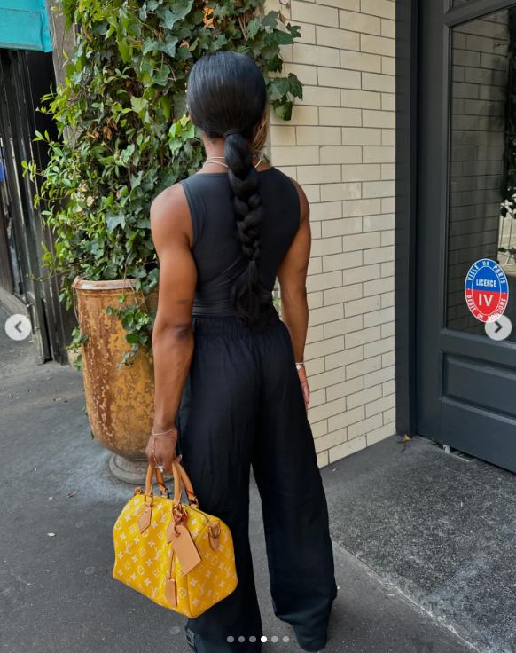 Simone Biles rocks an all-black ensemble and a striking yellow purse while on the sidewalk in Paris, France, posted in August 2024 | Source: Instagram.com/simonebiles