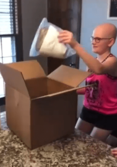 Taylor taking her new wig out of a box.│Source: facebook.com/SupportWigsForKids