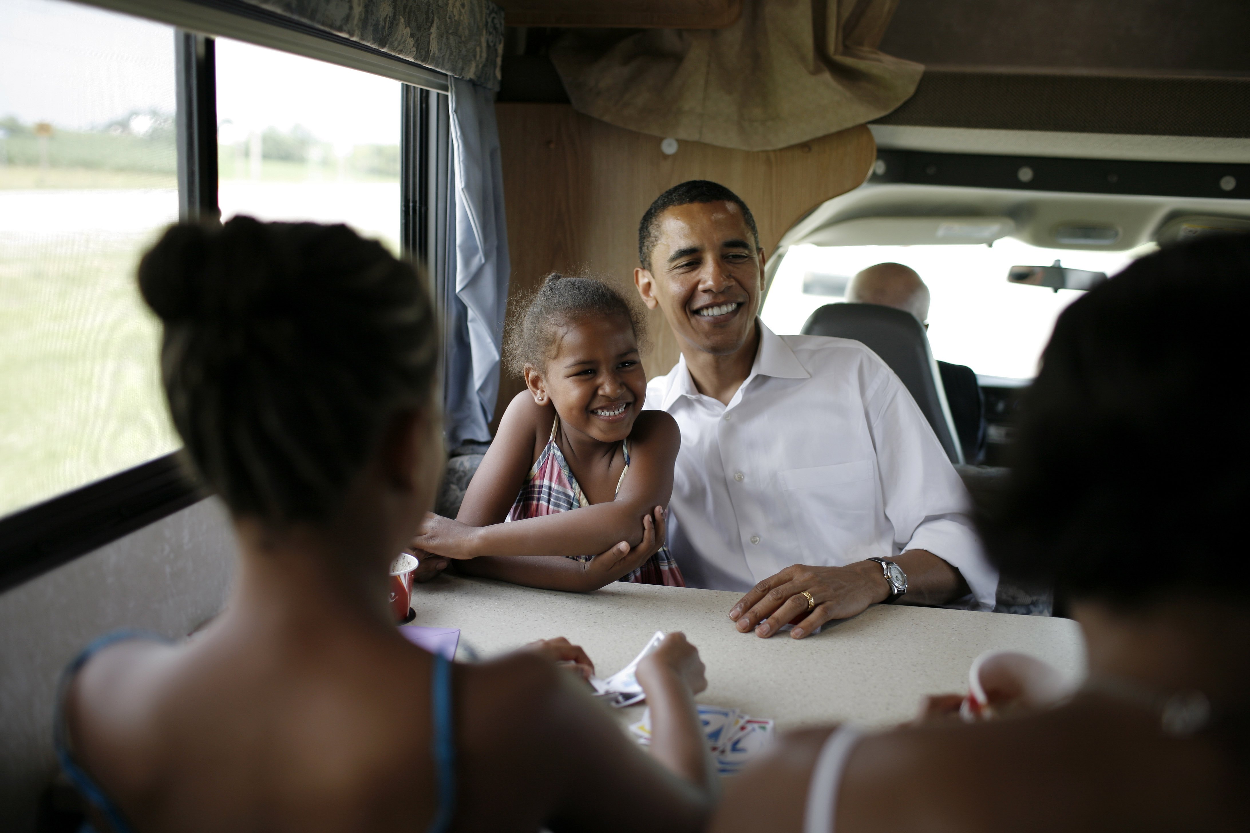 Michelle, Malia, Sasha and Barack Obama playing cards in their RV  while on a campaign swing between Oskaloosa and Pella, Iowa on July 4, 2007. | Source: Getty Images