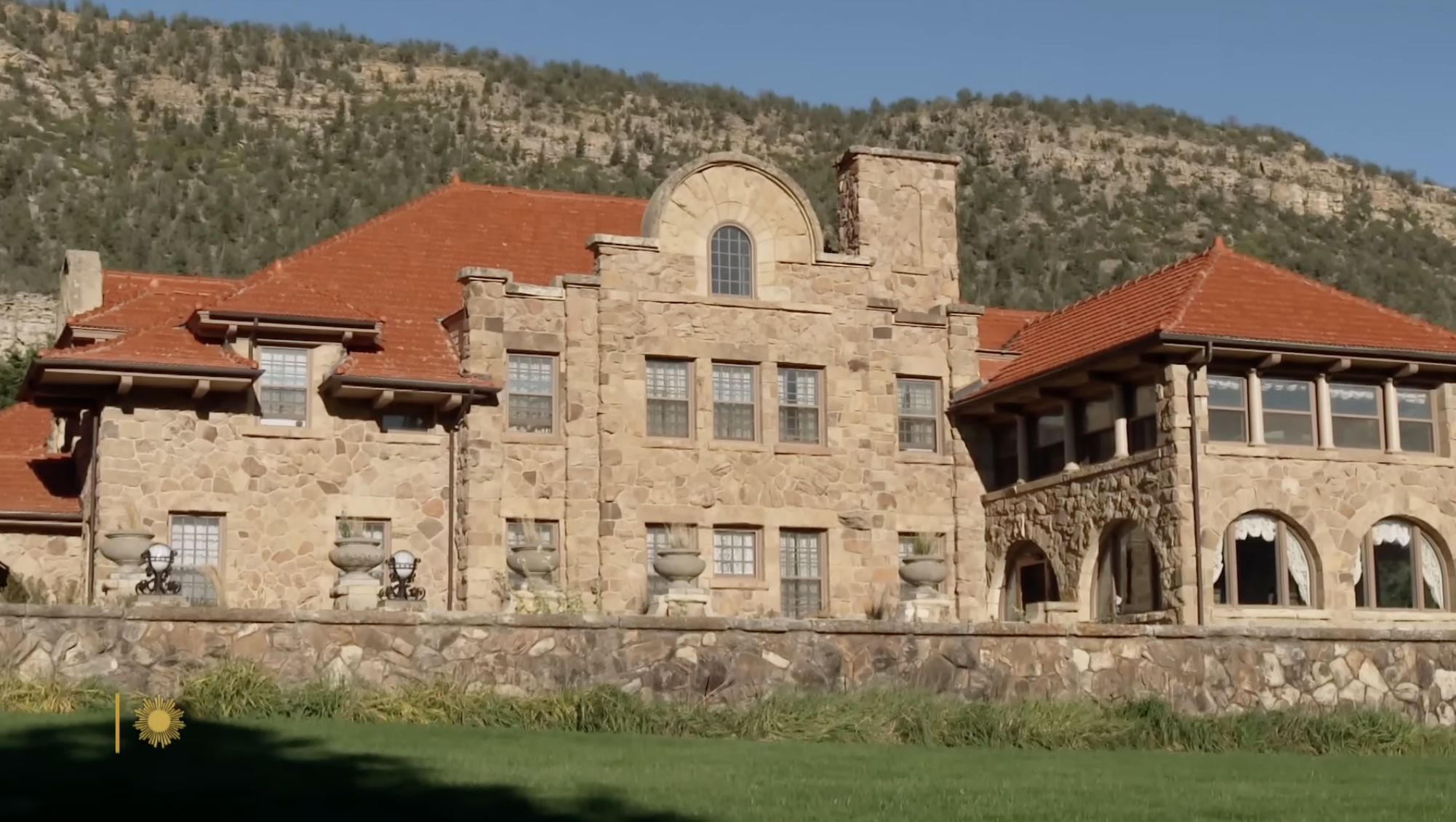 A grand stone mansion rises against a mountainous backdrop on one of Ted Turner’s expansive ranch properties. | Source: YouTube/CBS Sunday Morning