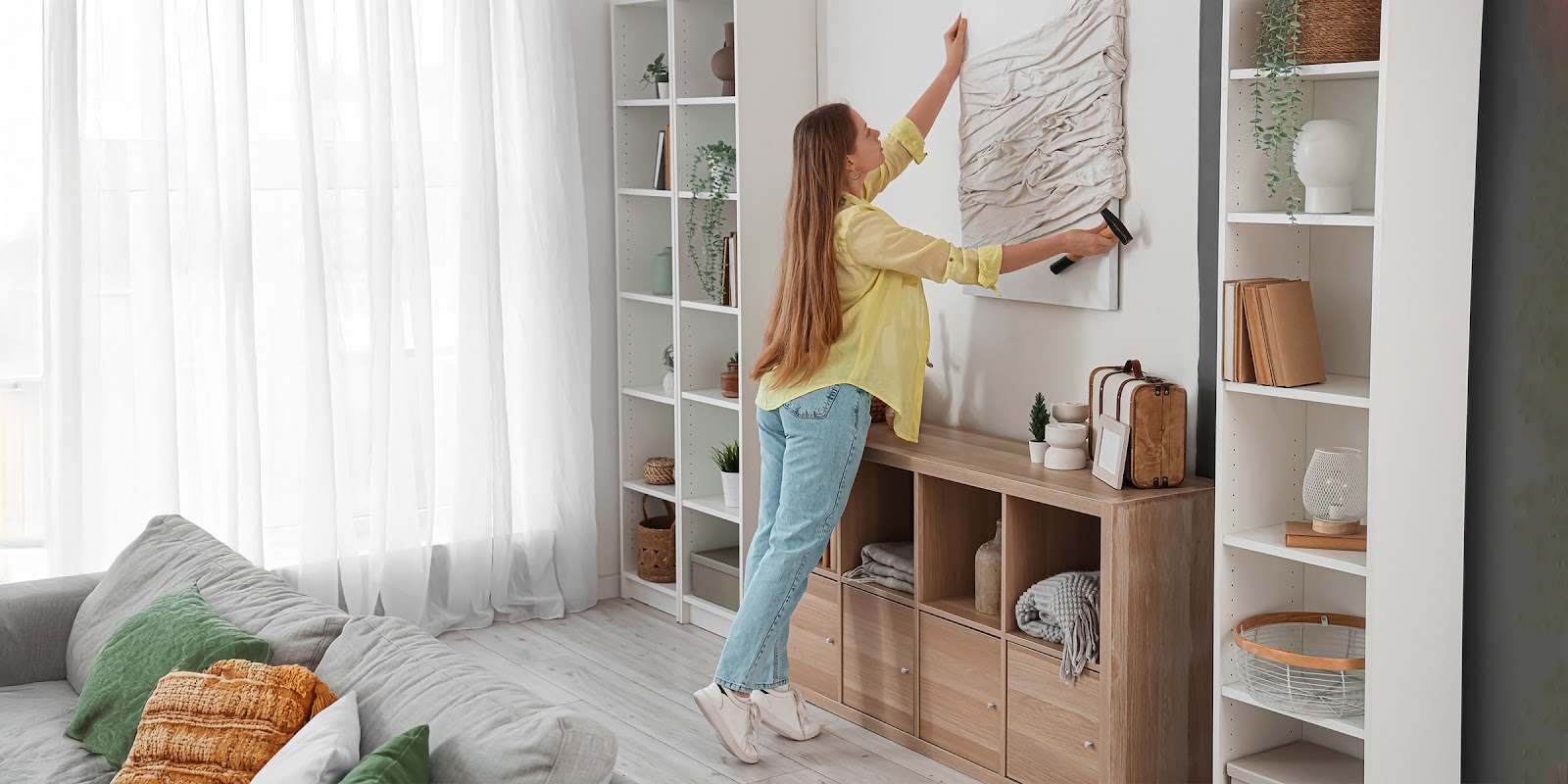 A woman hanging a painting | Source: Shutterstock