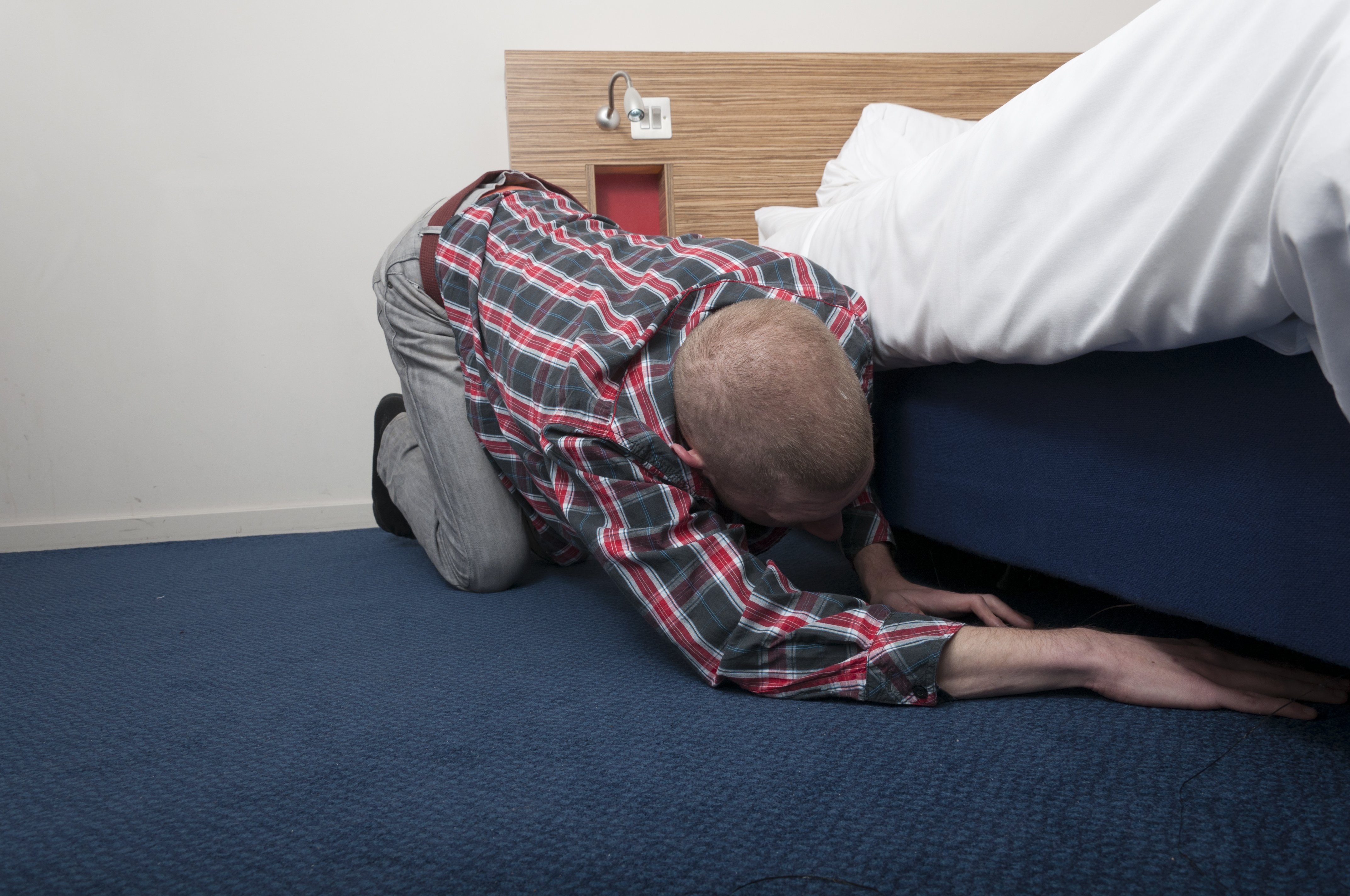 Man looking under the bed. Image credit: Shutterstock