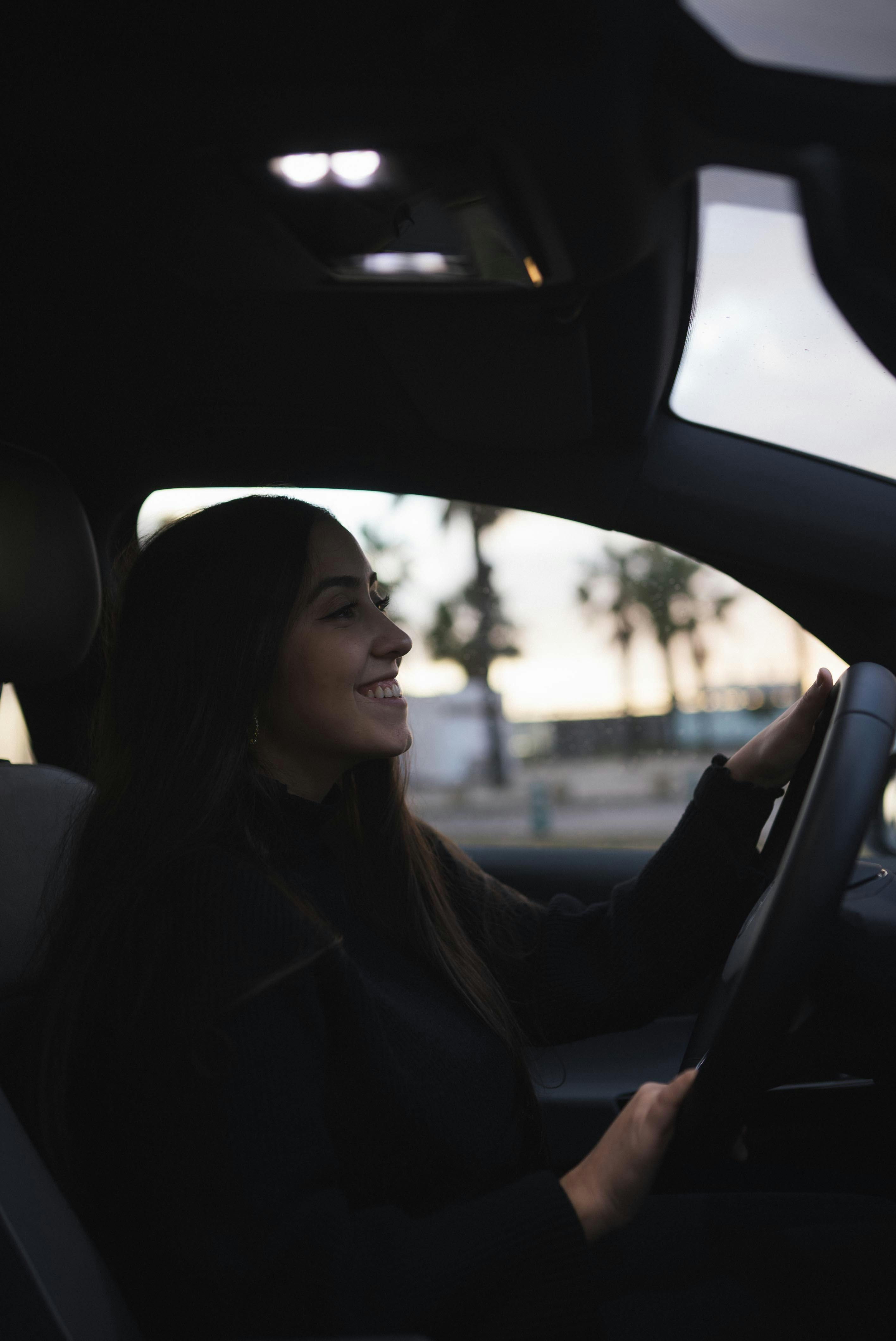A woman smiling in the driver's seat of a car | Source: Pexels