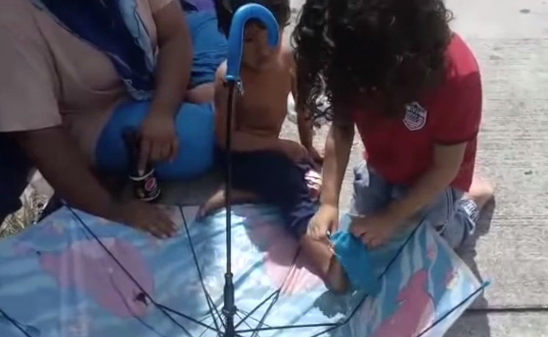 Cheikh colocándole los calcetines al niño sin hogar. Fuente: YouTube/Sahouli Cheikh Faizal
