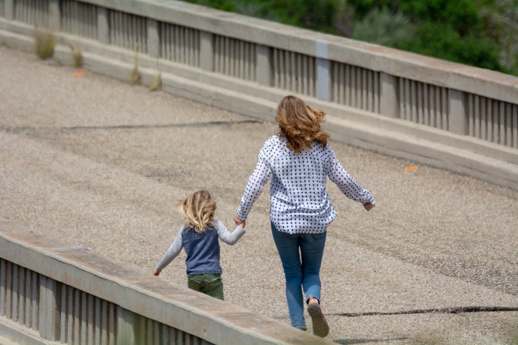 Mujer y una niña caminando por una carretera. | Imagen: Flickr