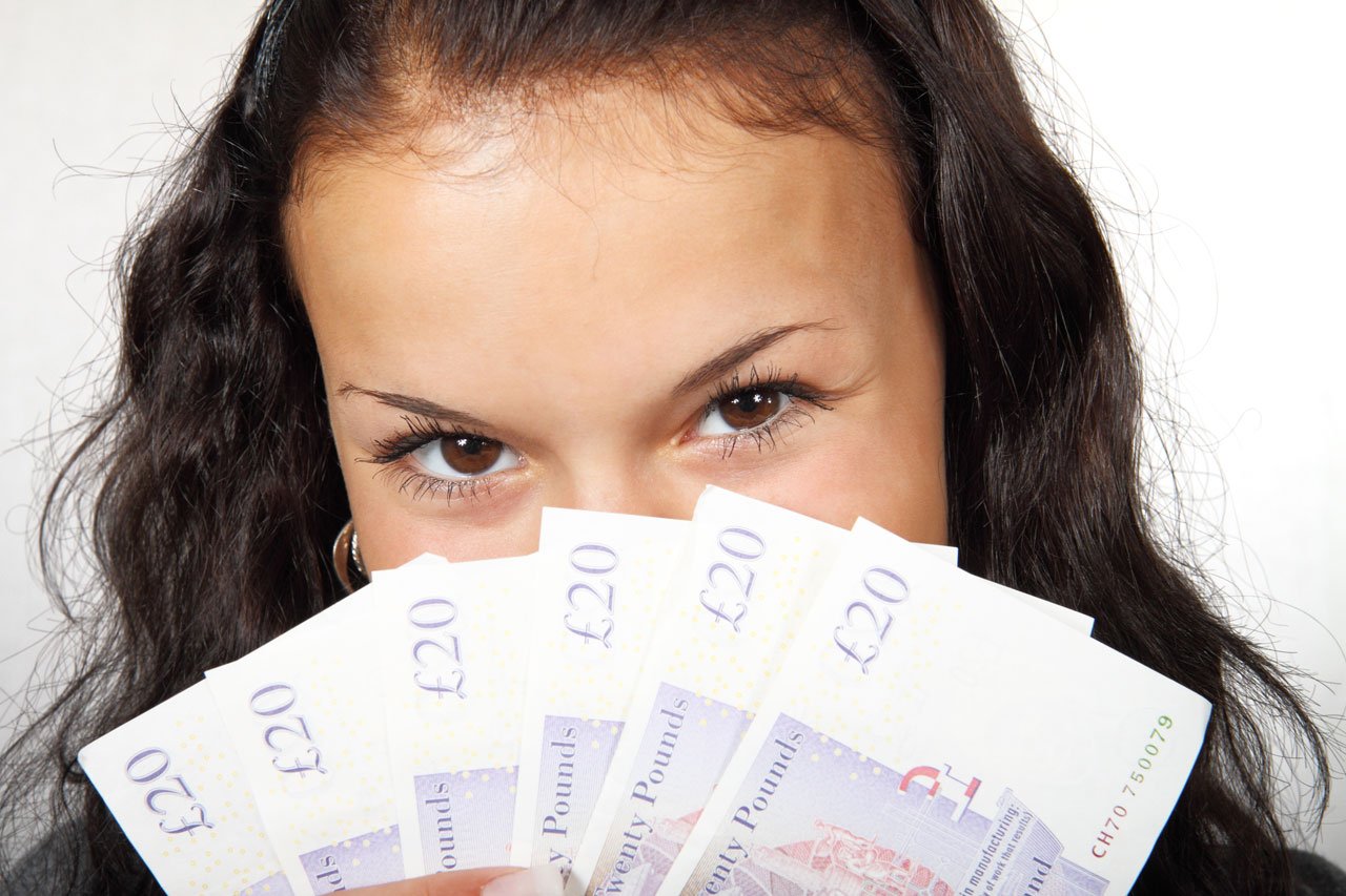 Mujer sosteniendo un puñado de billetes en forma de abanico que cubren su rostro. | Imagen: Public Domain Pictures Mujer sosteniendo un puñado de billetes en forma de abanico que cubren su rostro. | Imagen: Public Domain Pictures