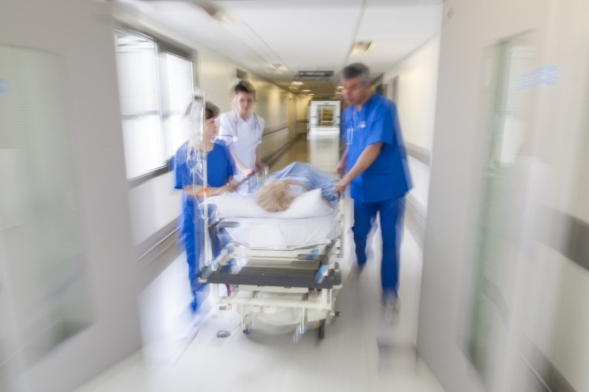 Personal médico empujando una camilla con una paciente a través de un pasillo en un hospital. | Imagen: PxHere