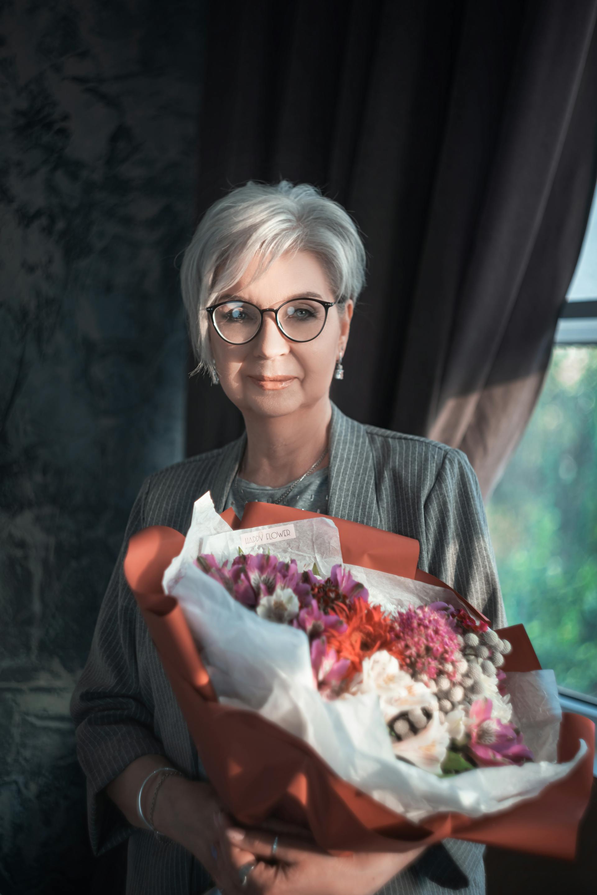 A smiling woman holding a bouquet of flowers | Source: Pexels